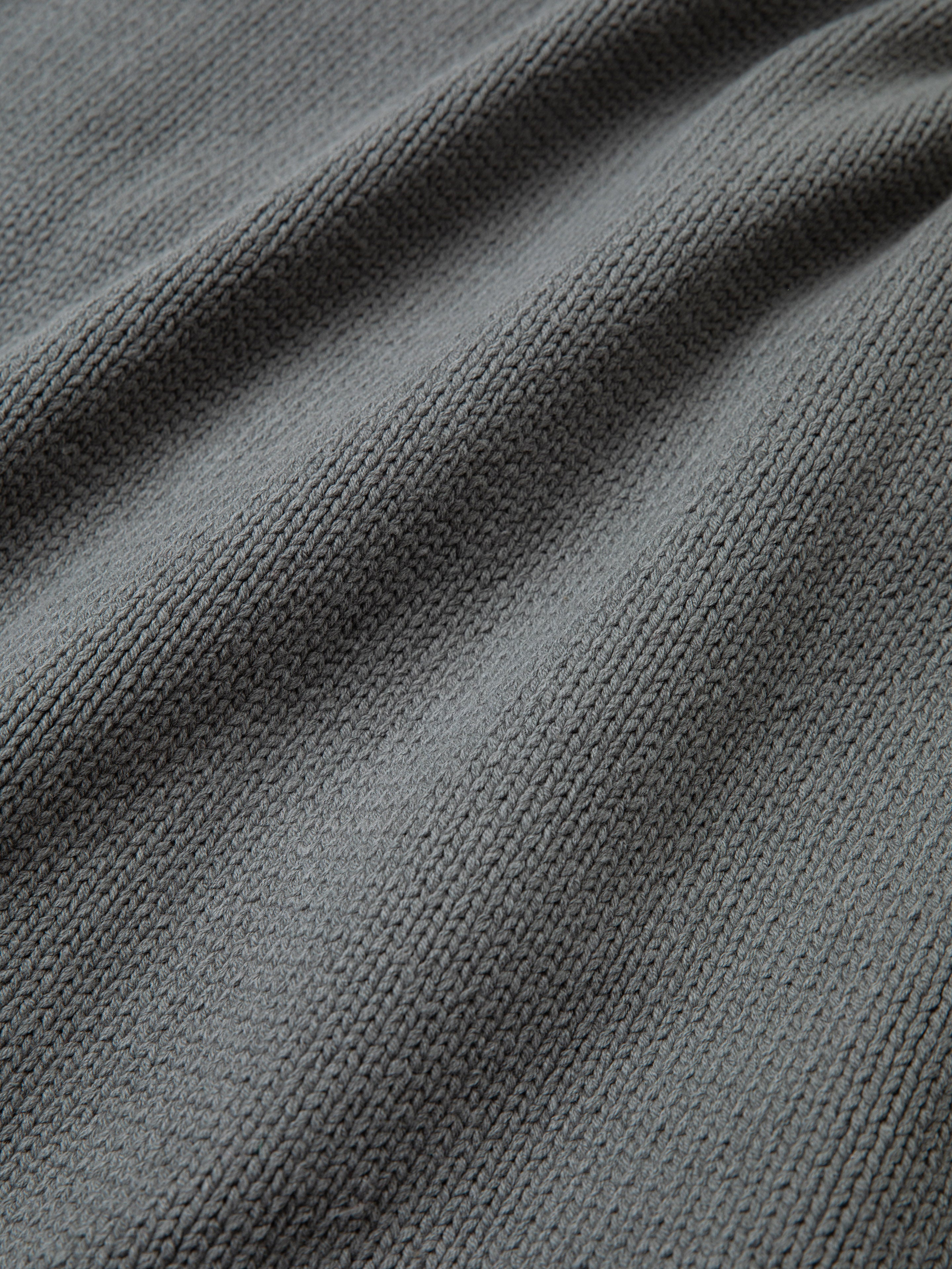Close-up of the Hunter Knit Collared Cardigan from FOUND, showcasing a textured grey knit fabric with a woven pattern and slight folds that evoke a cozy feel.