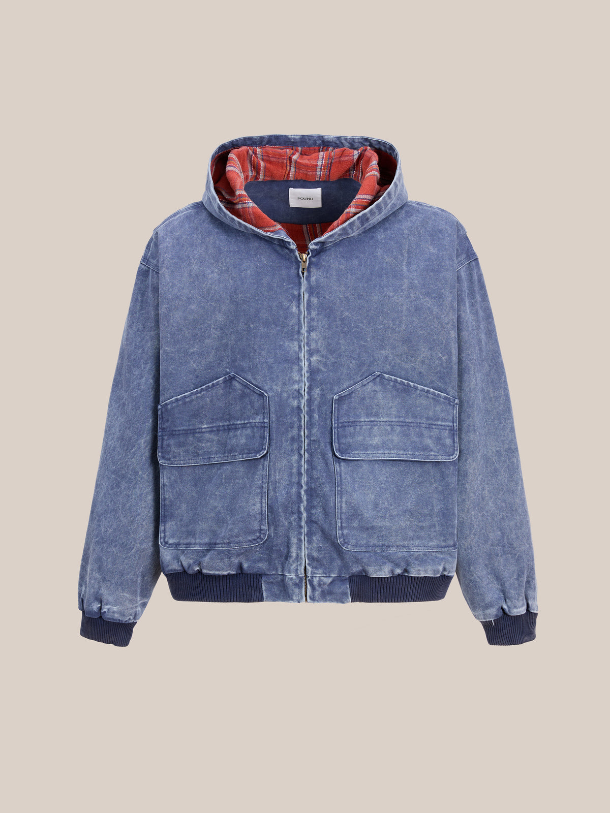 The FOUND Faded Canvas Work Hoodie in blue denim features a front zipper, two oversized flap pockets, ribbed cuffs and hem, and a red plaid lining, shown against a plain beige background.