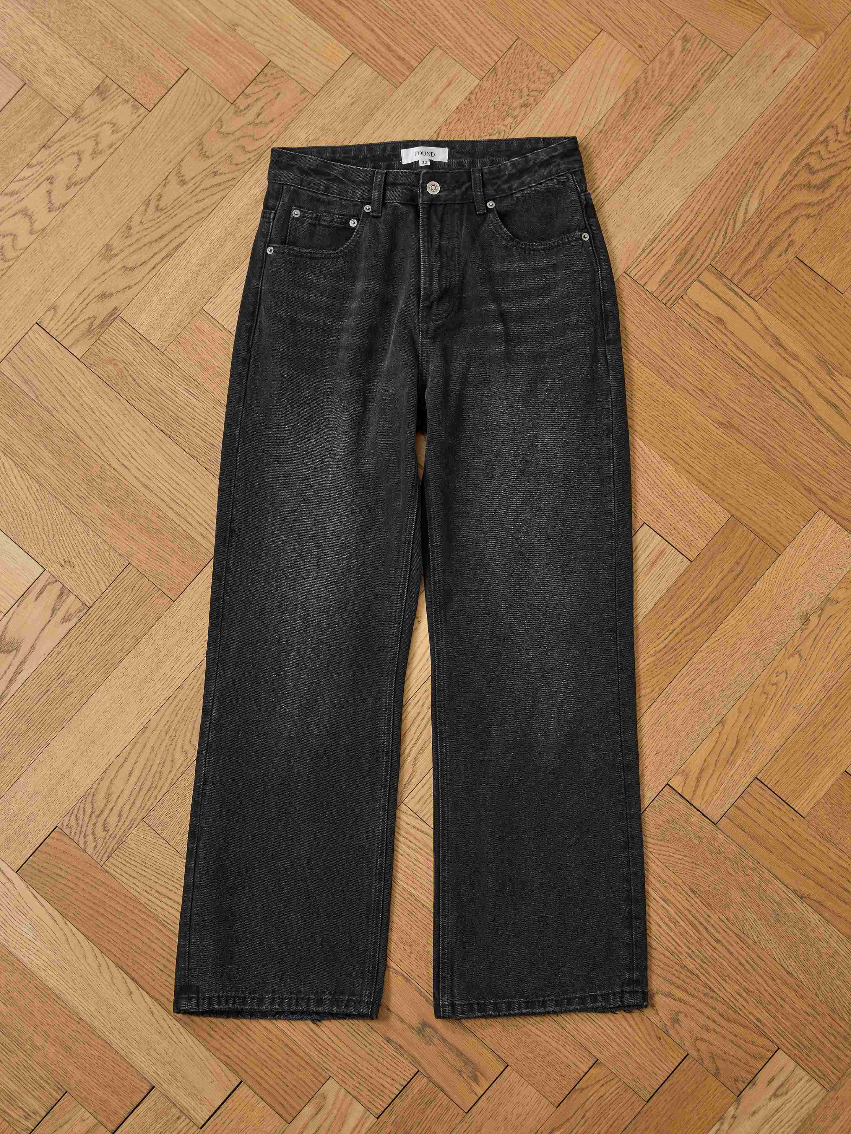 A pair of Found Flare Jeans is laid flat on a wooden herringbone floor.