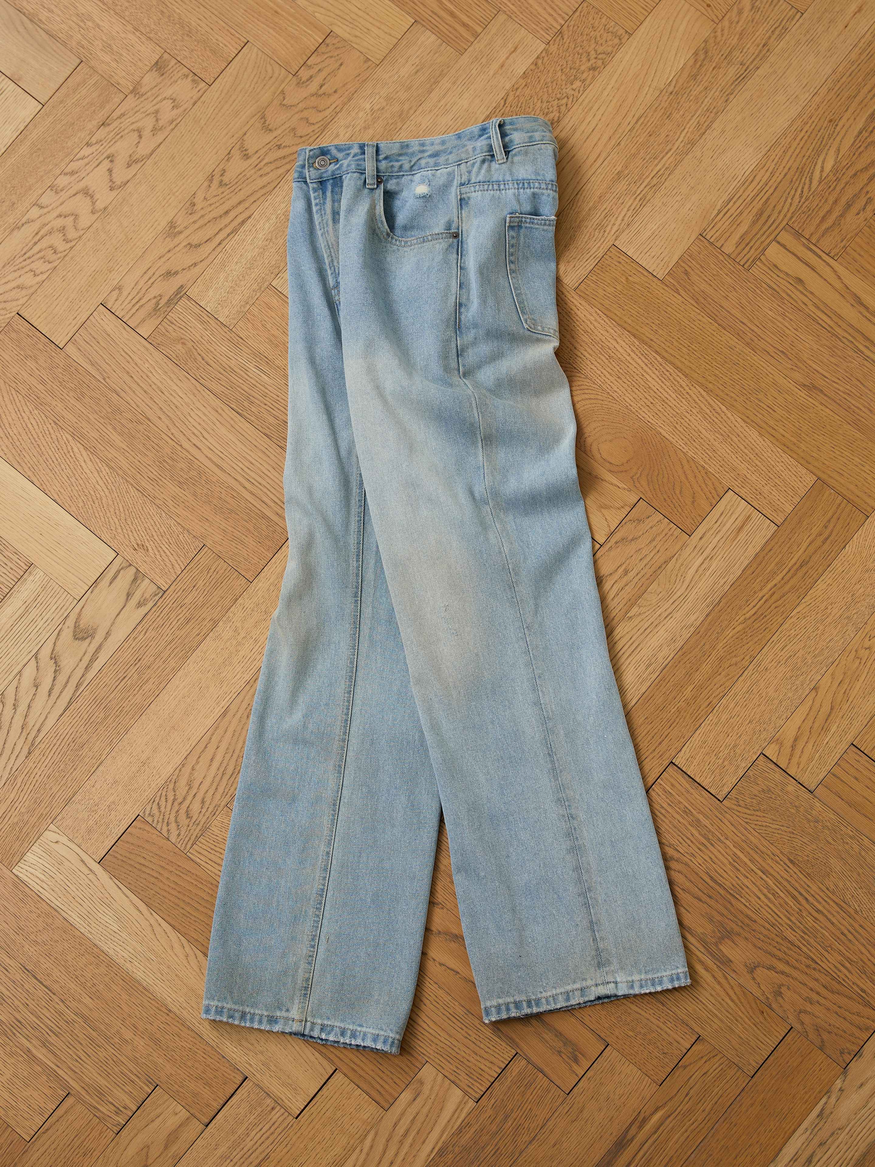 A pair of Found Flare Jeans in light blue denim with distressed hems is laid flat on a wooden parquet floor.