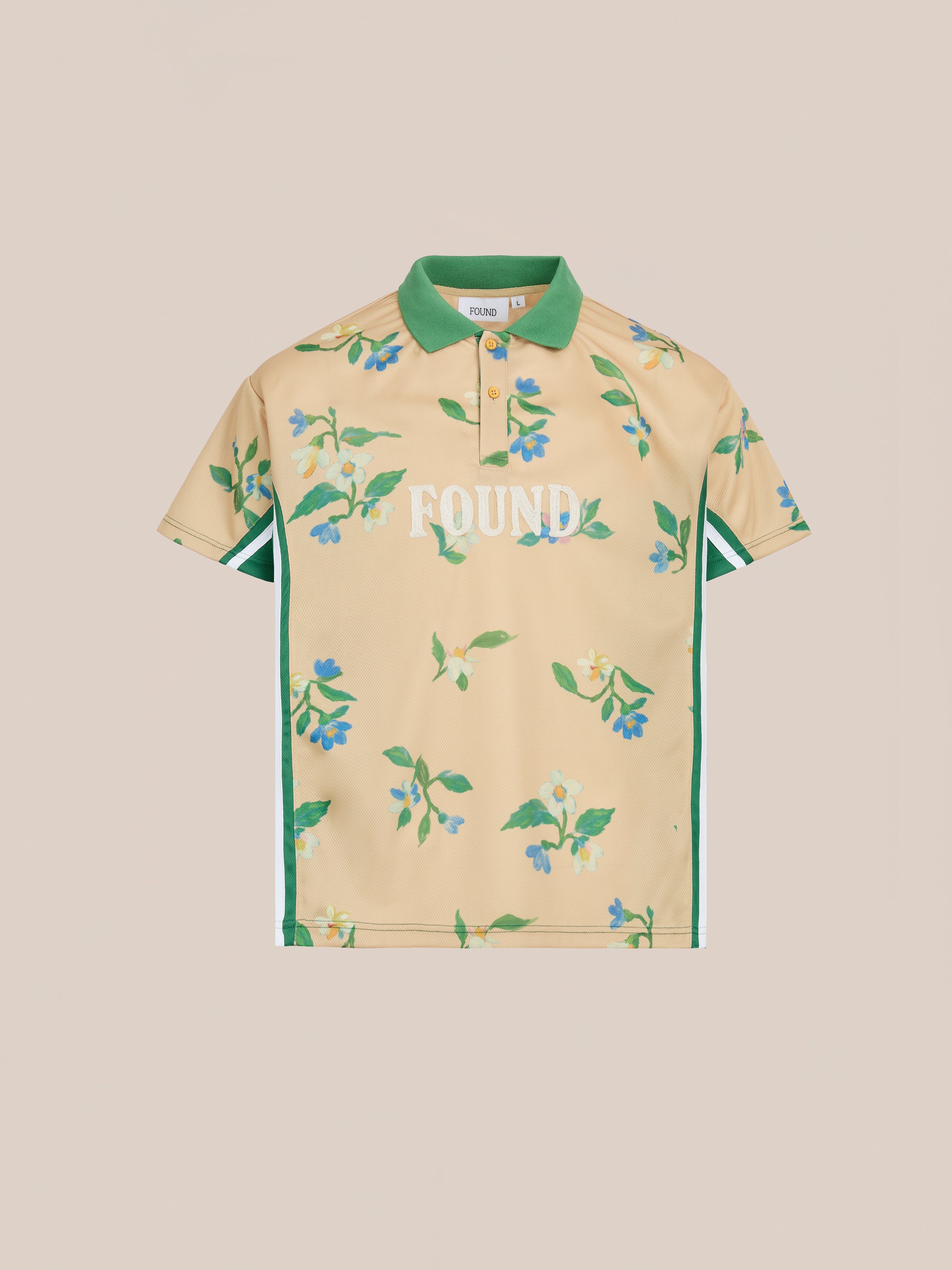The FOUND Floral Polo Jersey is a beige unisex polo with green floral print, green collar lining, side stripes, and "FOUND" in white on the front. Relaxed fit inspired by vintage sporting shirts for a timeless style.
