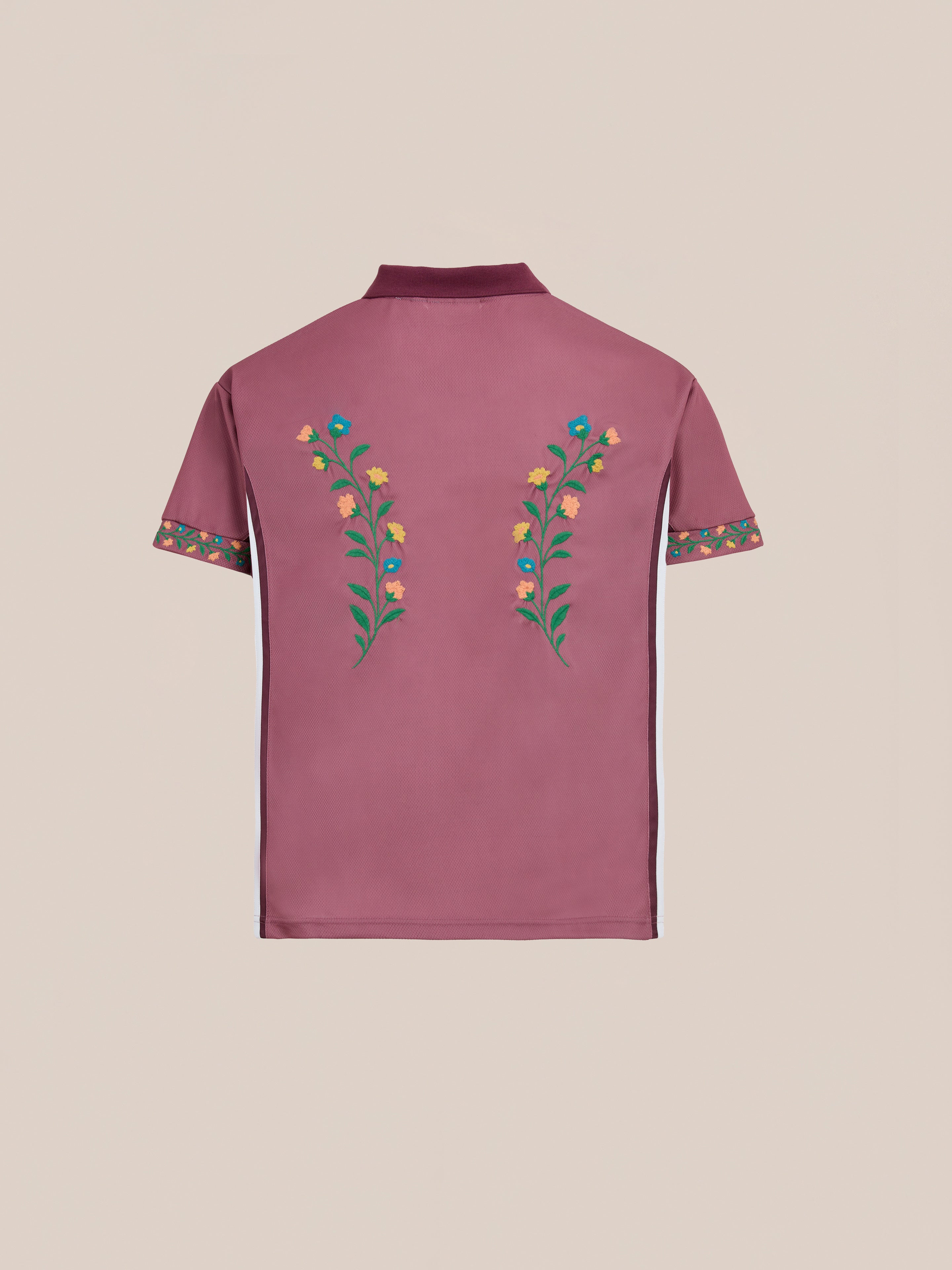 The FOUND Floral Polo Jersey is a maroon short-sleeved cotton polo with a collar, featuring floral embroidery on the back and sleeves and white side stripes, shown against a plain background.