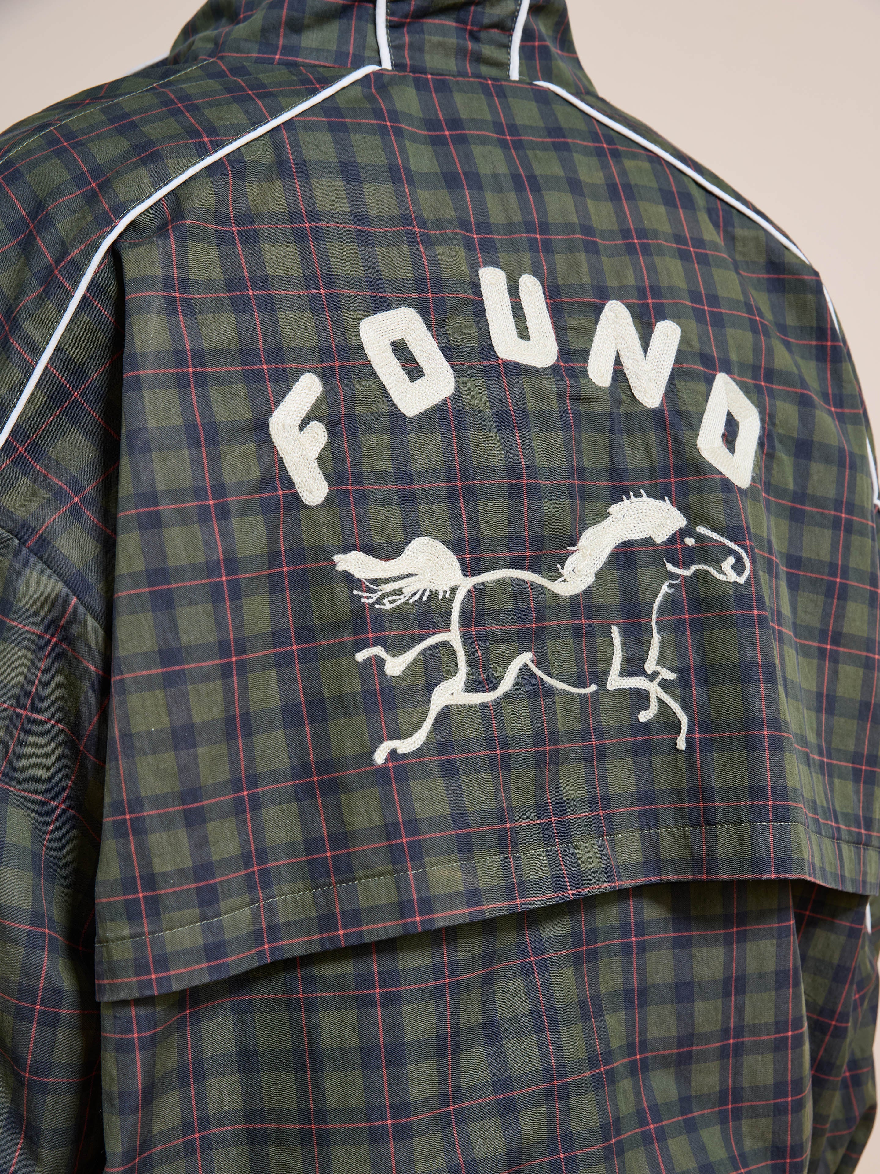 Back view of the FOUND Forest Plaid Track Jacket with white piping, "FOUND" lettering, and an embroidered horse design on the upper back.