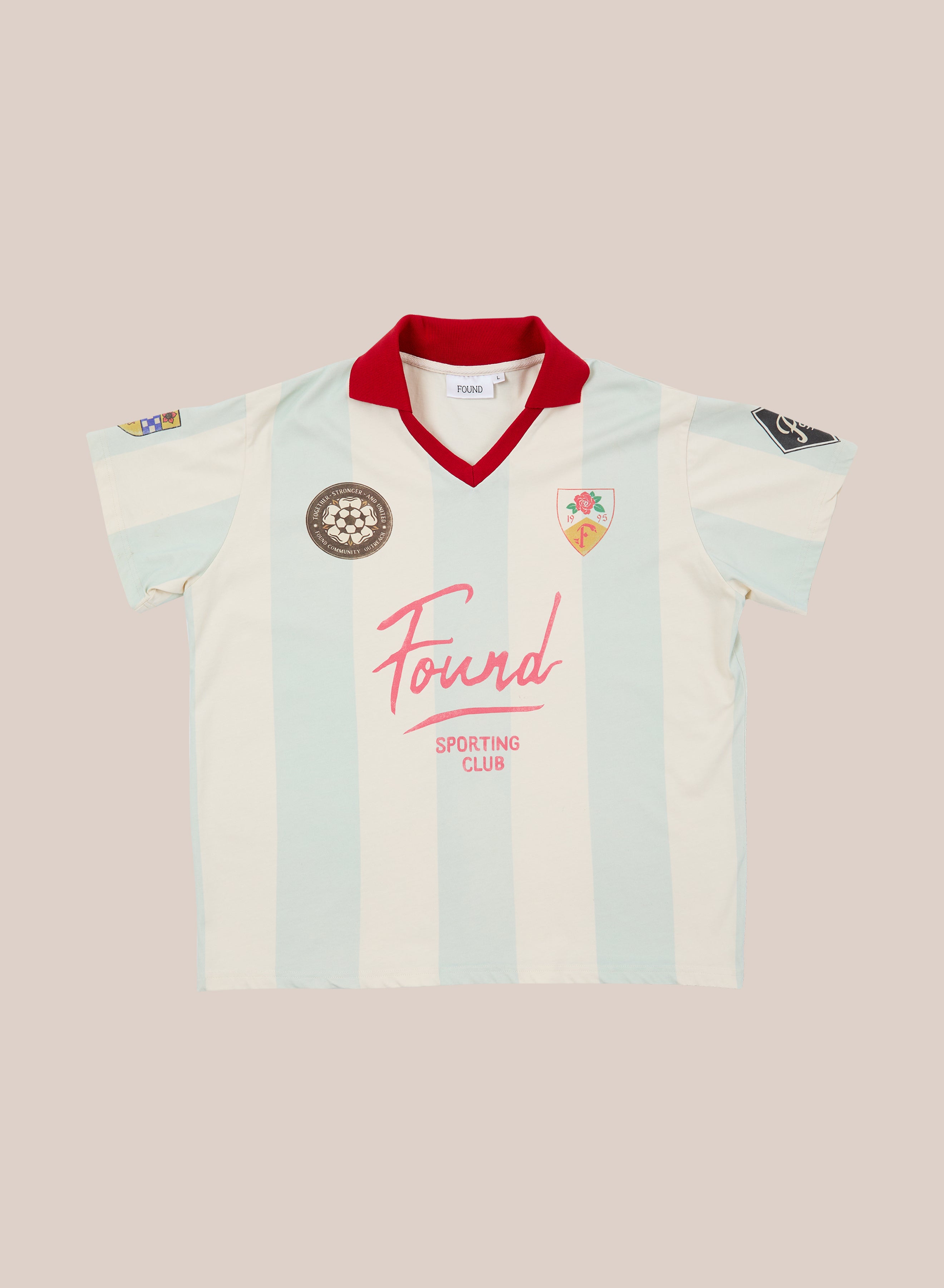 FOUND’s Found Club Short Sleeve Jersey features light blue and white vertical stripes, a red collar, embroidered patches, and “Found Sporting Club” text on the front—a classic-inspired unisex sportswear piece from FOUND.