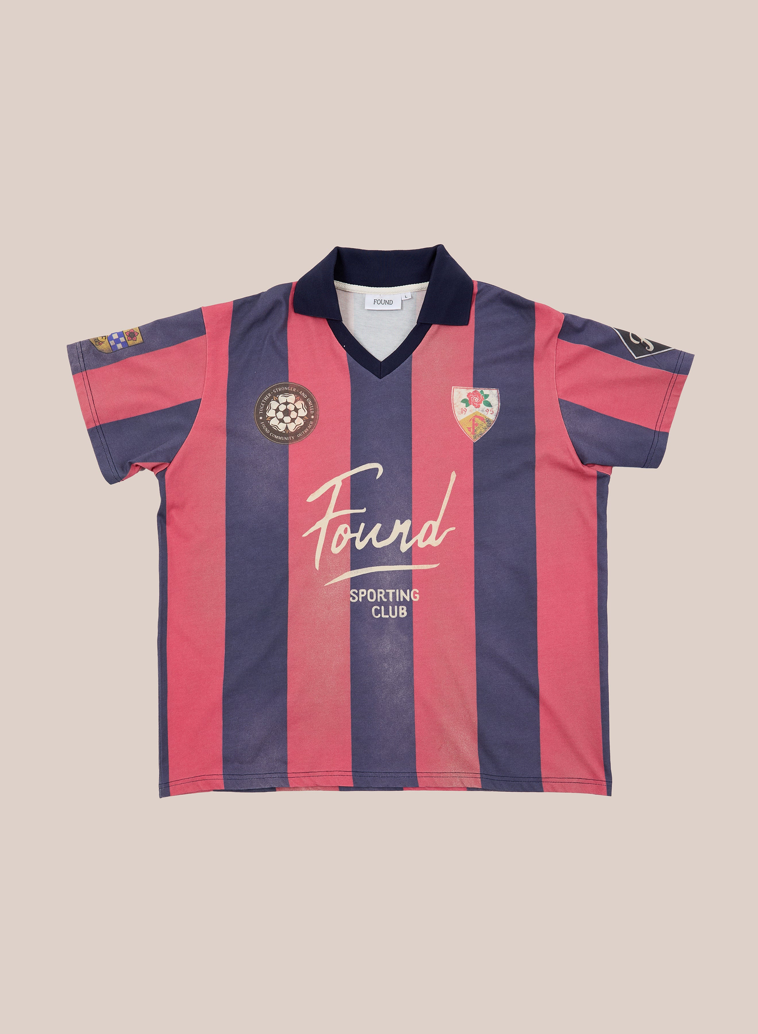 Introducing the FOUND Found Club Short Sleeve Jersey—a unisex, relaxed-fit soccer jersey showcasing bold wide vertical navy and pink stripes, a classic black collar, and an array of embroidered patches including “Found Sporting Club” on the front. Perfect for anyone who loves a vintage football shirt vibe.