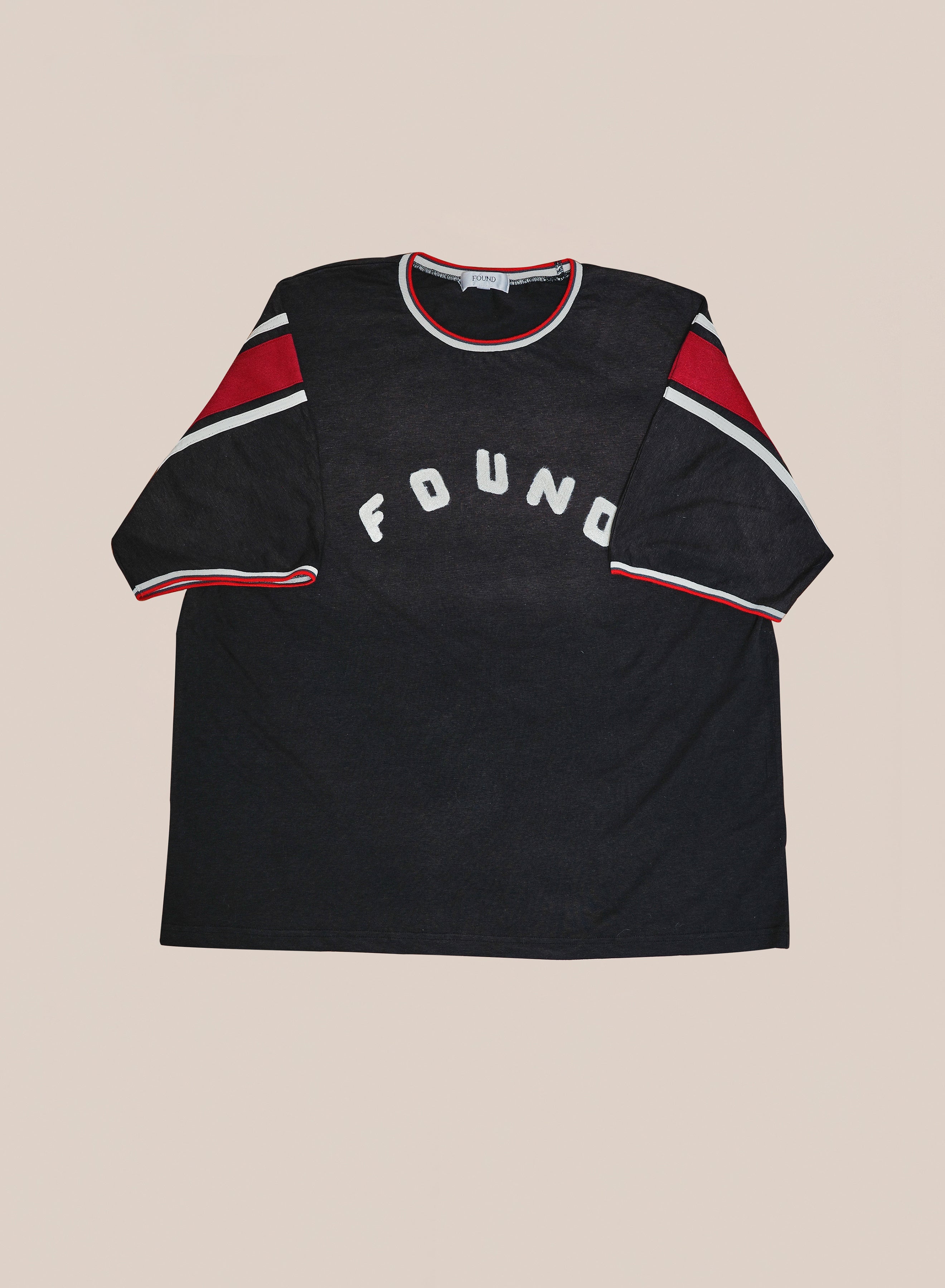 The FOUND Foundation Practice Jersey is a black short-sleeve tee with red and white accents on the sleeves and collar, featuring "FOUND" in white on the front. Vintage athletic styling delivers a classic look.