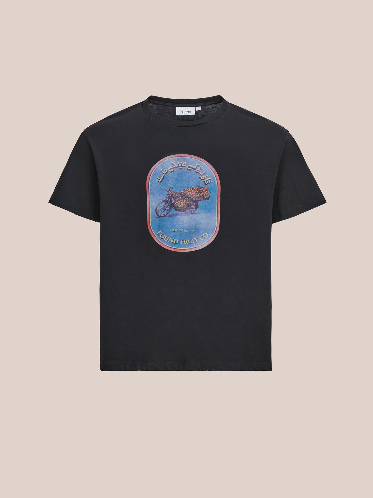 The FOUND Fruit Co Tee is a black unisex relaxed fit shirt with a central fruit graphic and Arabic script, inspired by vintage fruit stand styles.