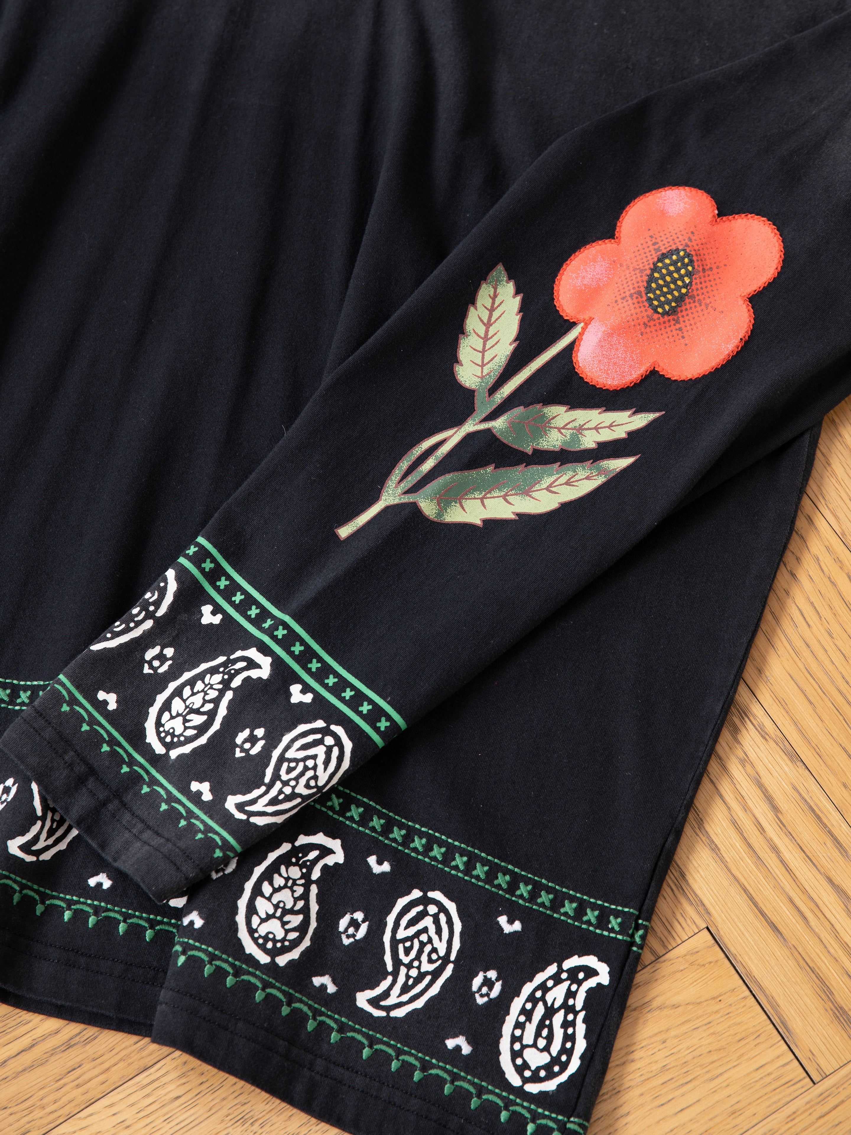 The FOUND Garden Bloom Embroidered LS Tee features a relaxed fit, red flower and green leaf embroidery on the sleeve, and white paisley designs bordered with green trim near the cuff and hem.