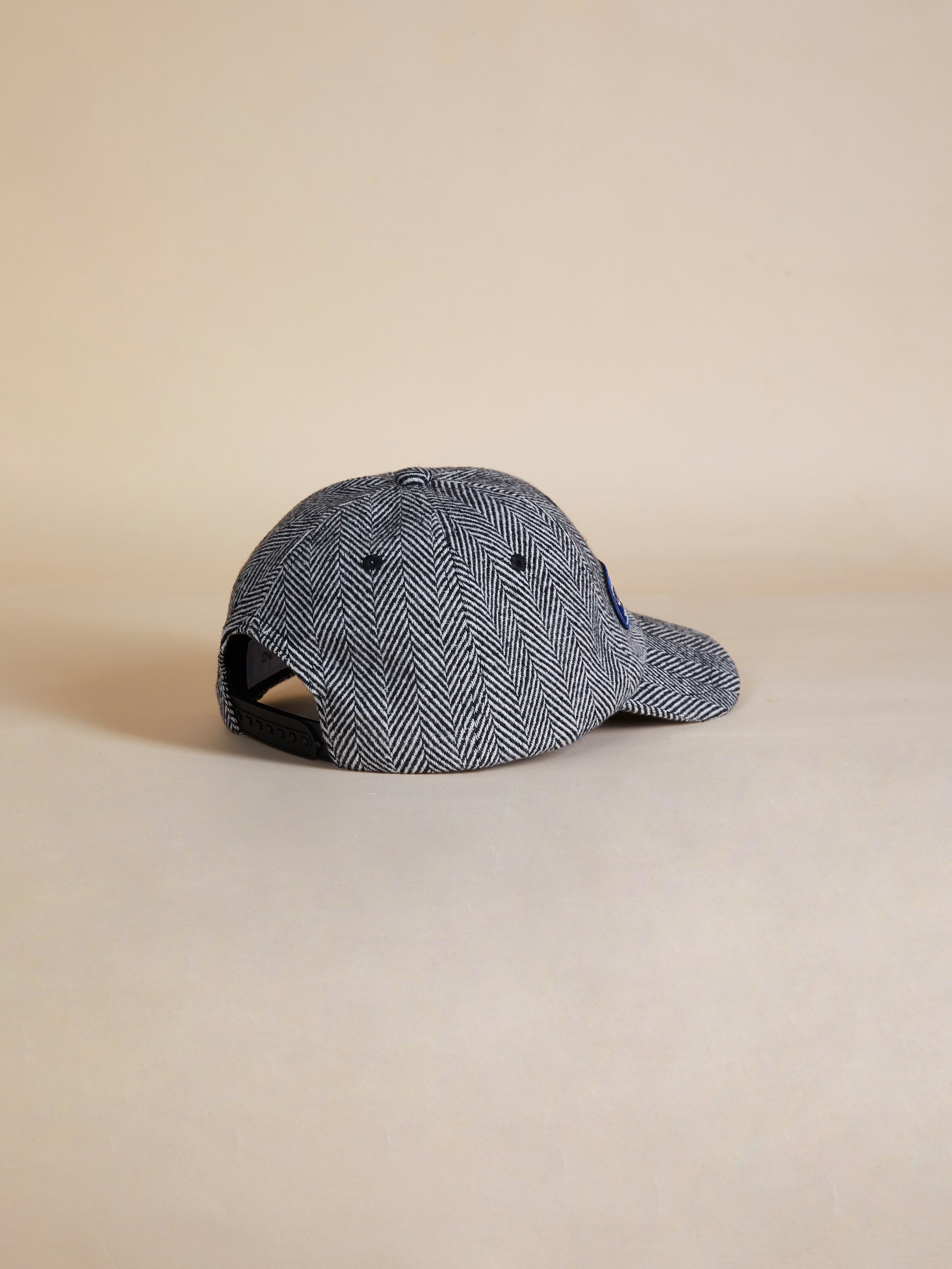 A Found Herringbone Tweed Patch Cap on a beige background.