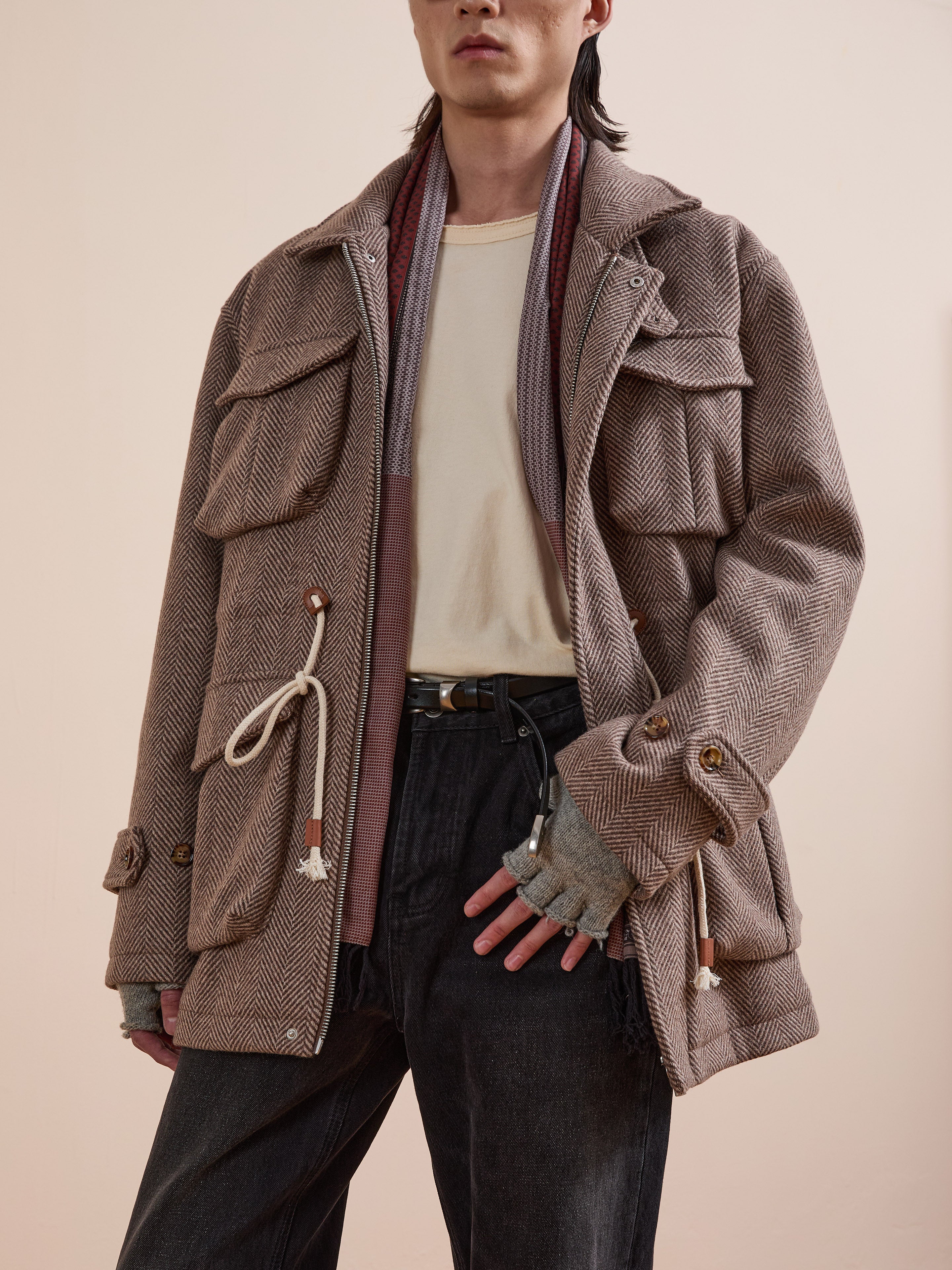 A person wears the FOUND Herringbone Wool Barn Jacket with large pockets, a cream shirt, gray scarf, fingerless gloves, and black pants against a neutral background.