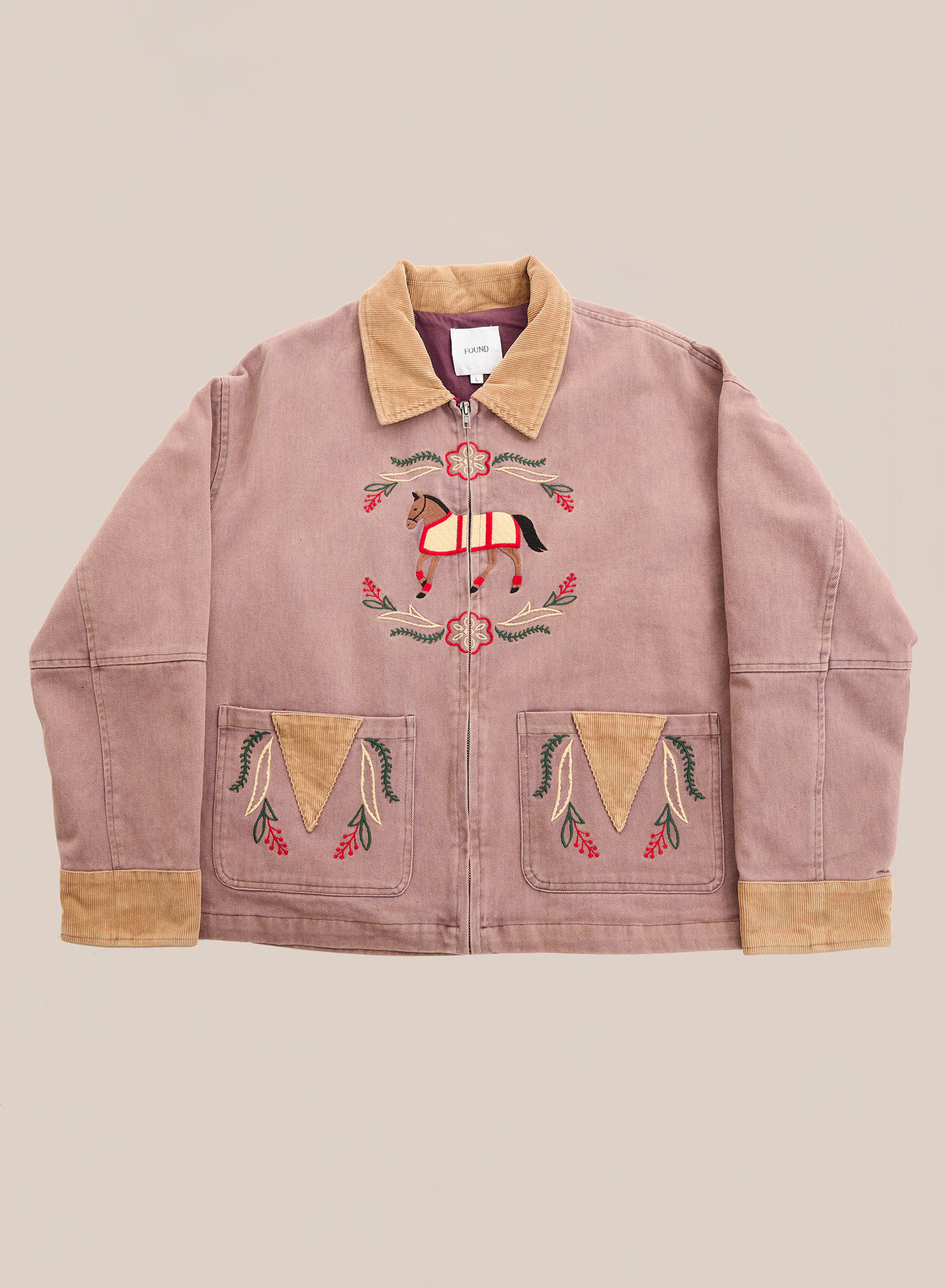 The FOUND Horse Crest Work Jacket in light mauve features a tan collar, pockets, and embroidered horse and floral motifs, honoring equestrian heritage.
