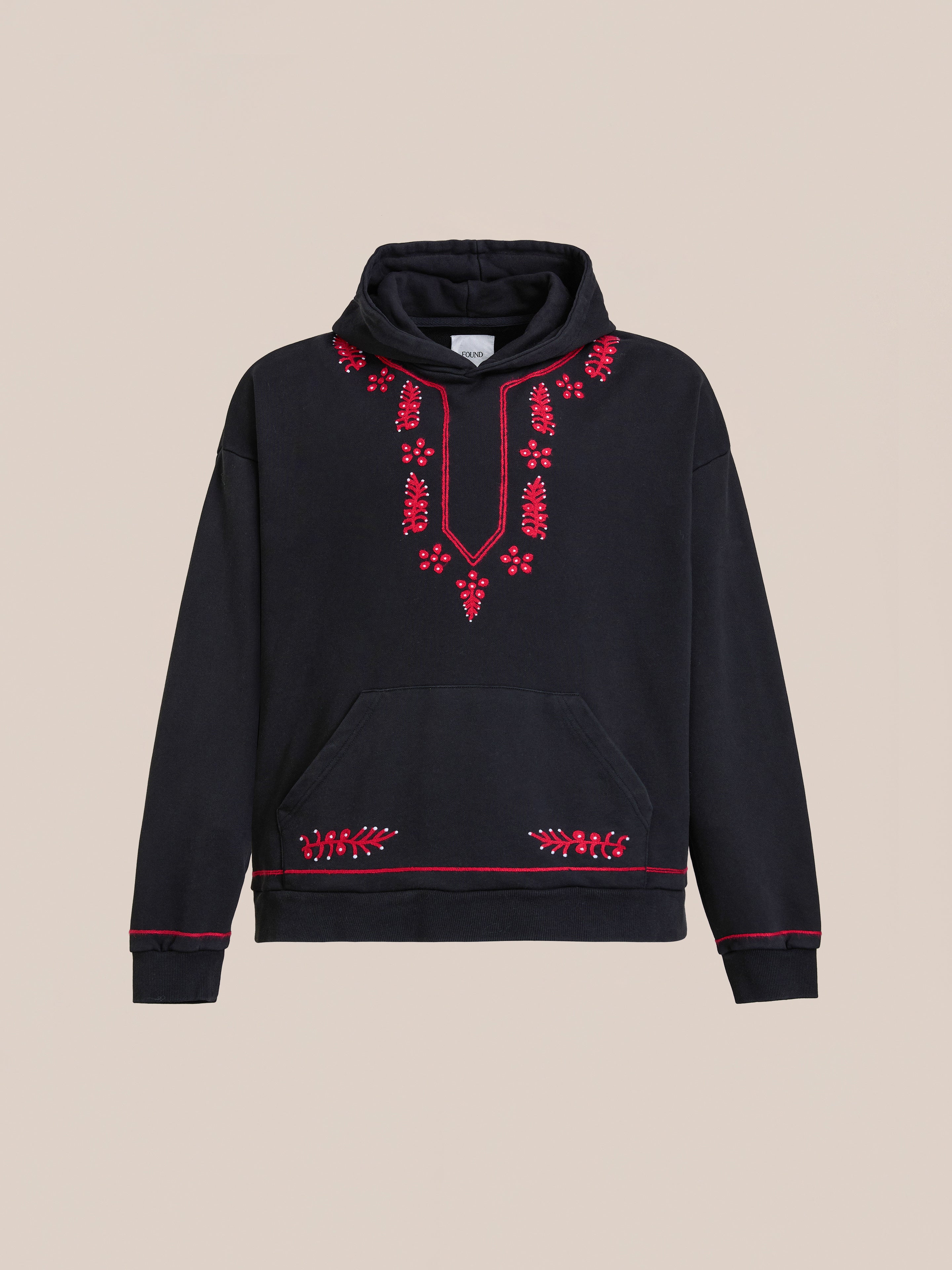 The FOUND Indus Embroidered Hoodie features red floral embroidery on the chest, hem, and sleeves, a vintage wash finish, and a front kangaroo pocket.
