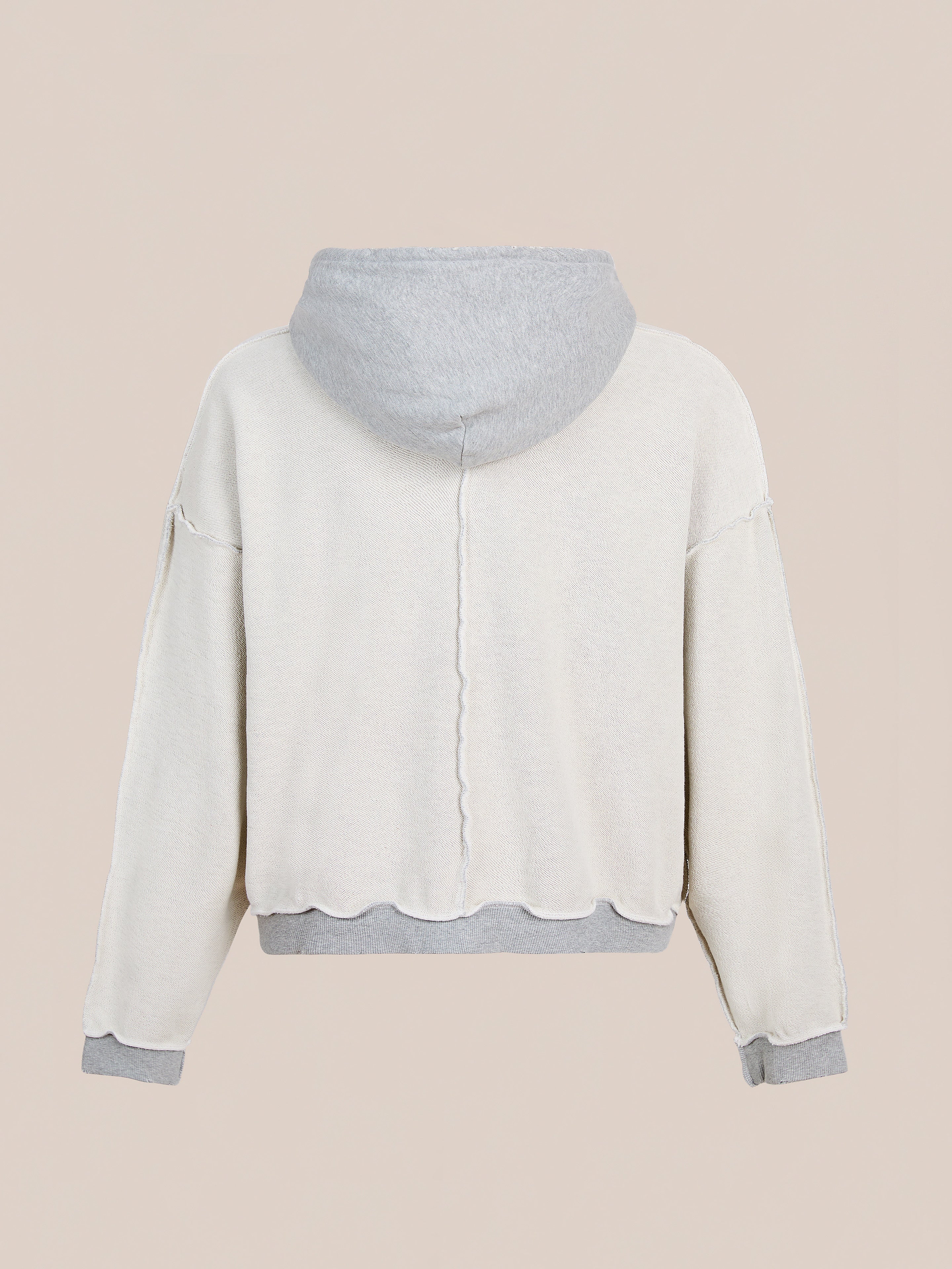 The FOUND Deconstructed Terry Zip Up Hoodie is a unisex, relaxed fit in light beige with gray cuffs, waistband, and hood. Made from mid-weight cotton with dropped shoulders. Shown from the back against a plain beige background.