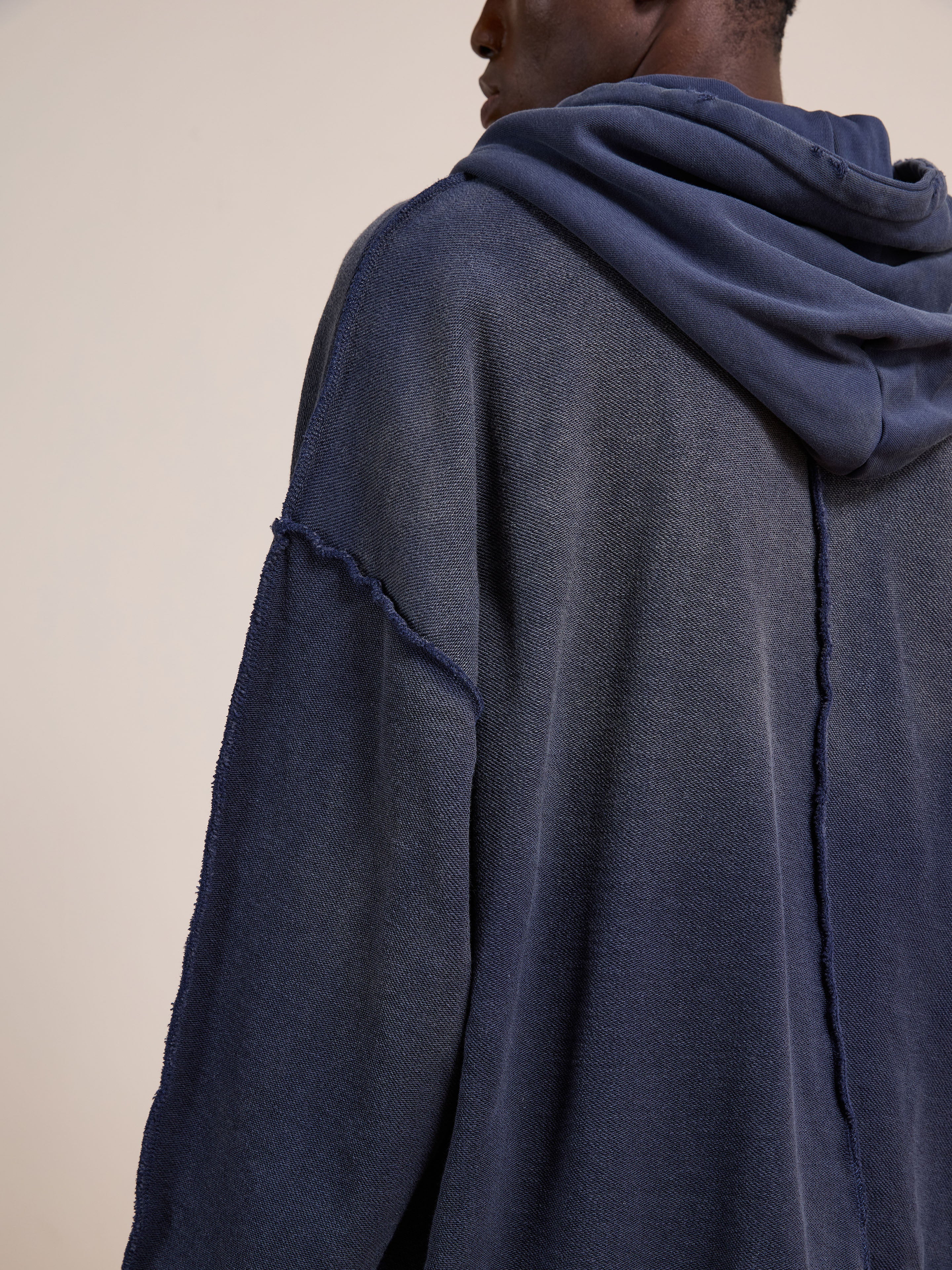 A person wearing the FOUND Deconstructed Terry Zip Up Hoodie in relaxed fit navy blue with exposed seam details, shown from the back and side.