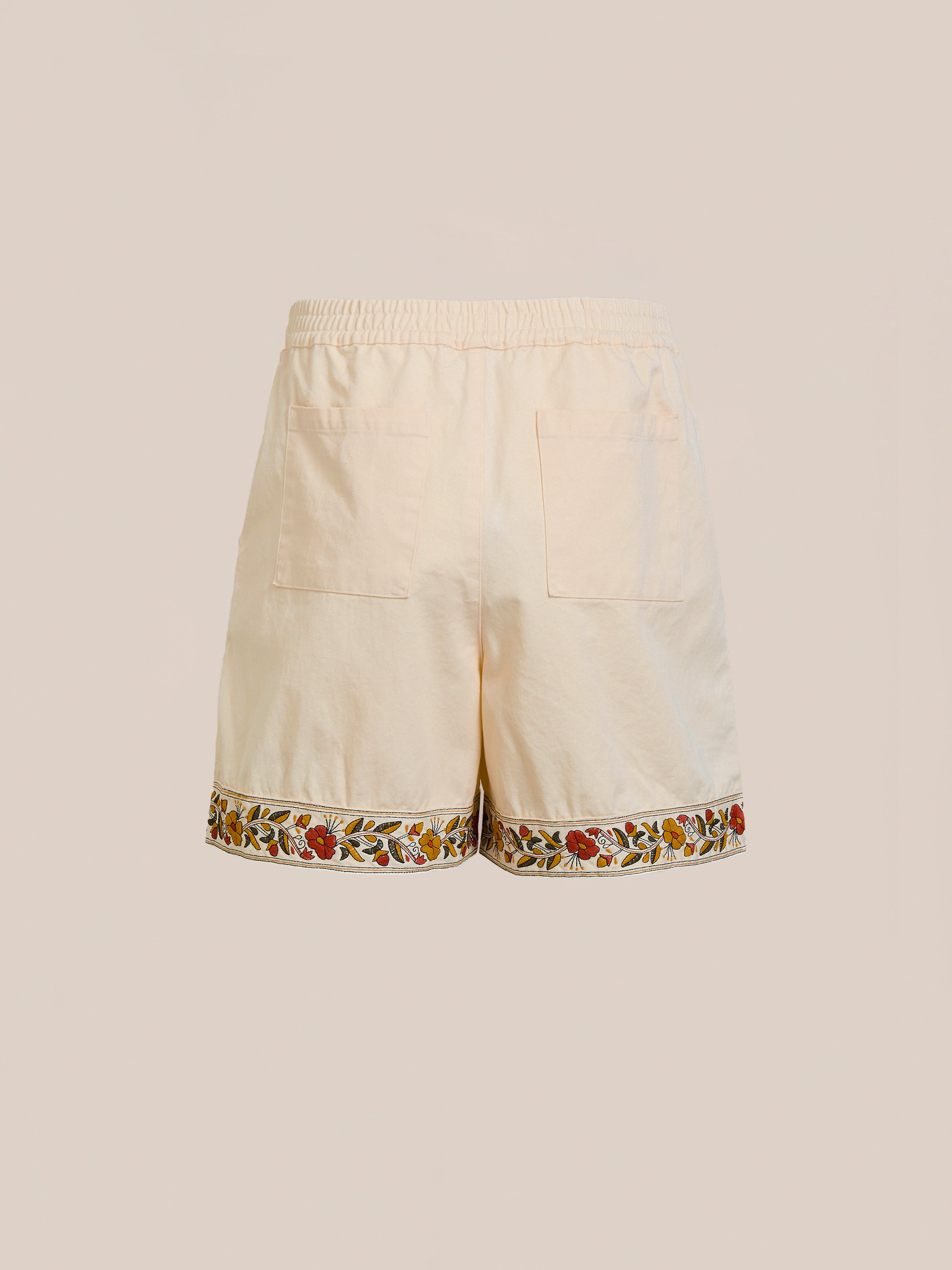 Discover FOUND's Kantha Floral Work Shorts, made from 100% cotton in beige. They boast a comfy elastic waistband, floral embroidery on the hem, and two back pockets. Ideal for highlighting their intricate design against a simple background.