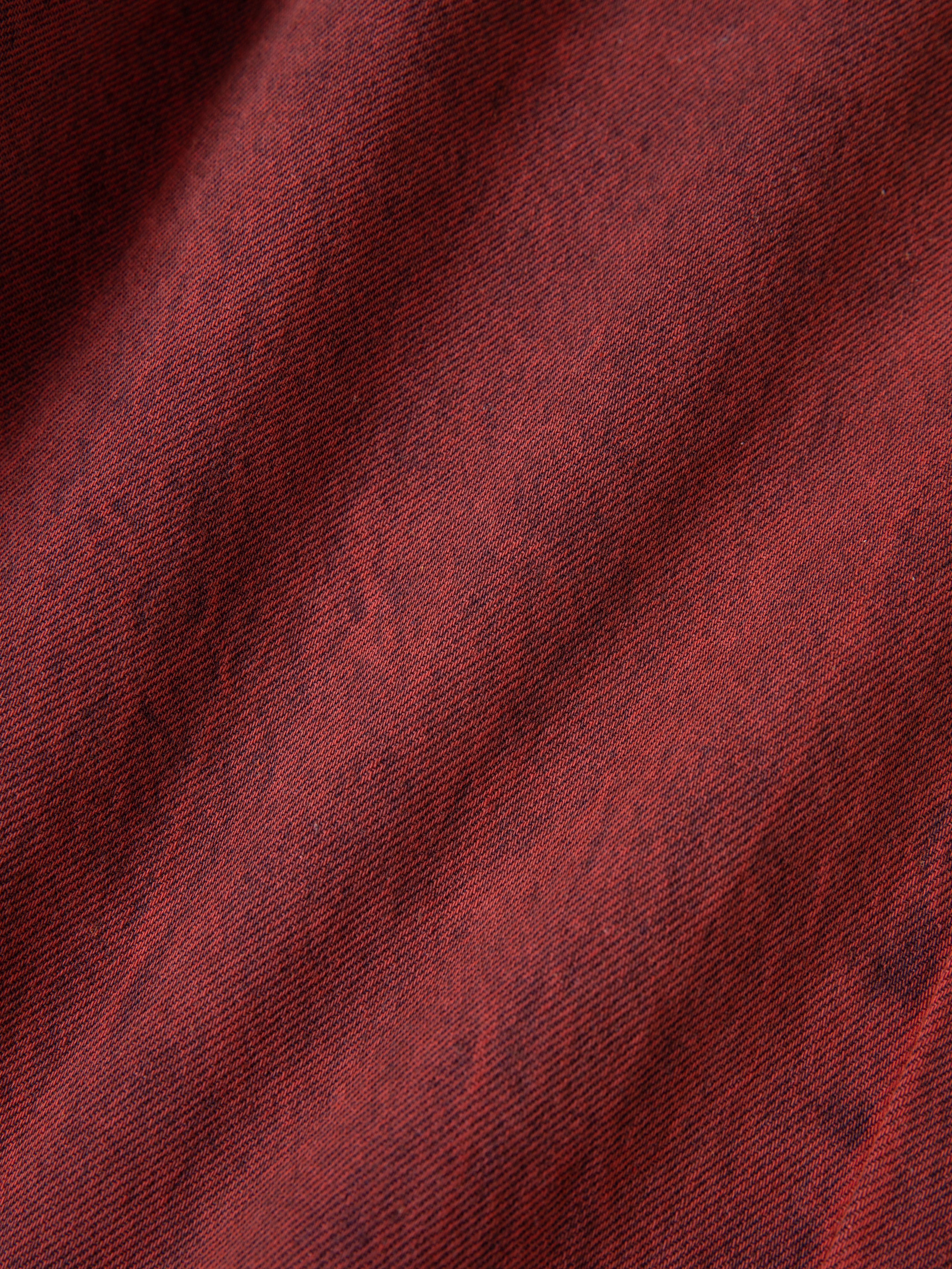 Close-up of FOUND Lacy Jean Jorts in vintage red, crafted from 100% cotton denim with visible weave texture and gentle folds, creating soft shadows on the surface.