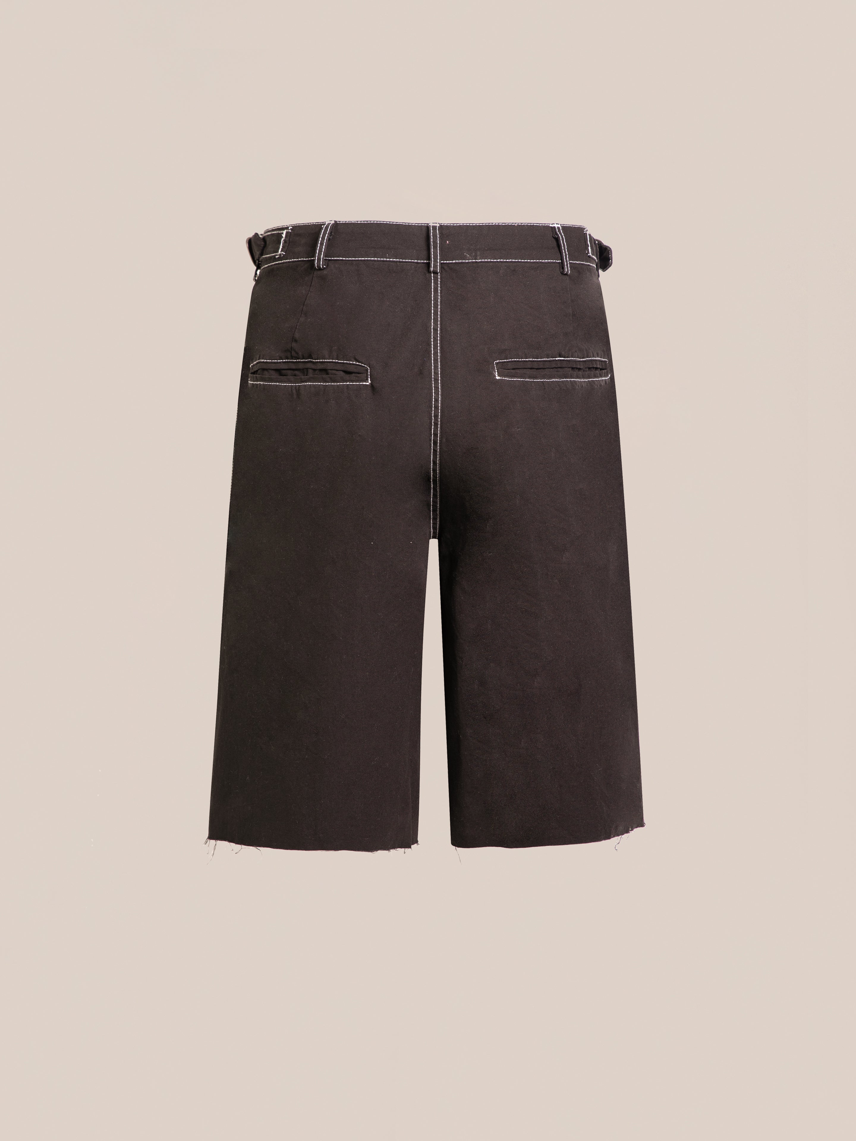 Back view of FOUND's Lucca Black Contrast Pocket Trouser Shorts in cotton twill, with white stitching, belt loops, two welt pockets, and raw hems, shown on a plain beige background.