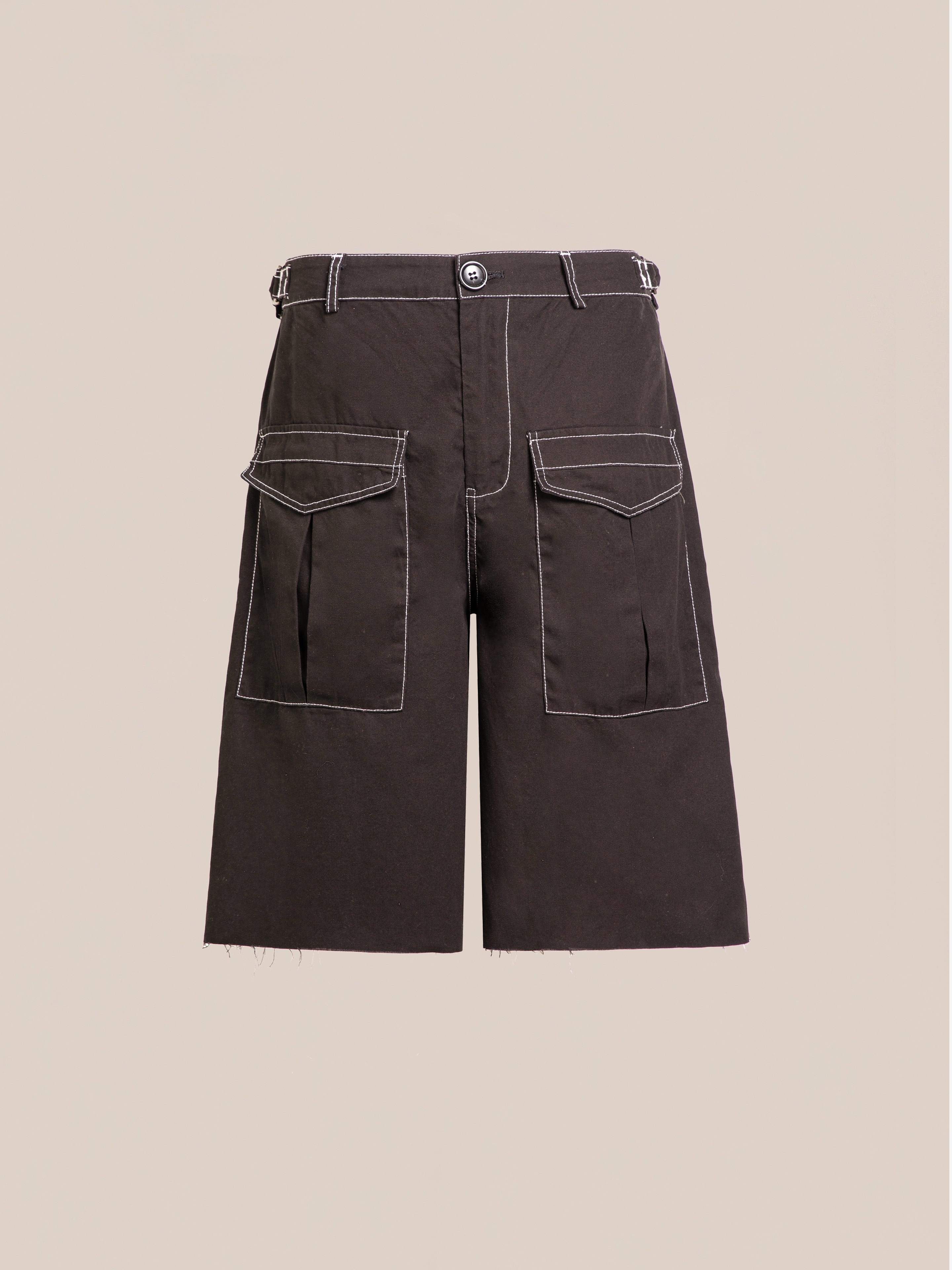 The Lucca Black Contrast Pocket Trouser Shorts by FOUND feature white stitching, two large front pockets, a relaxed fit, button closure, and belt loops. They are displayed against a plain beige background.