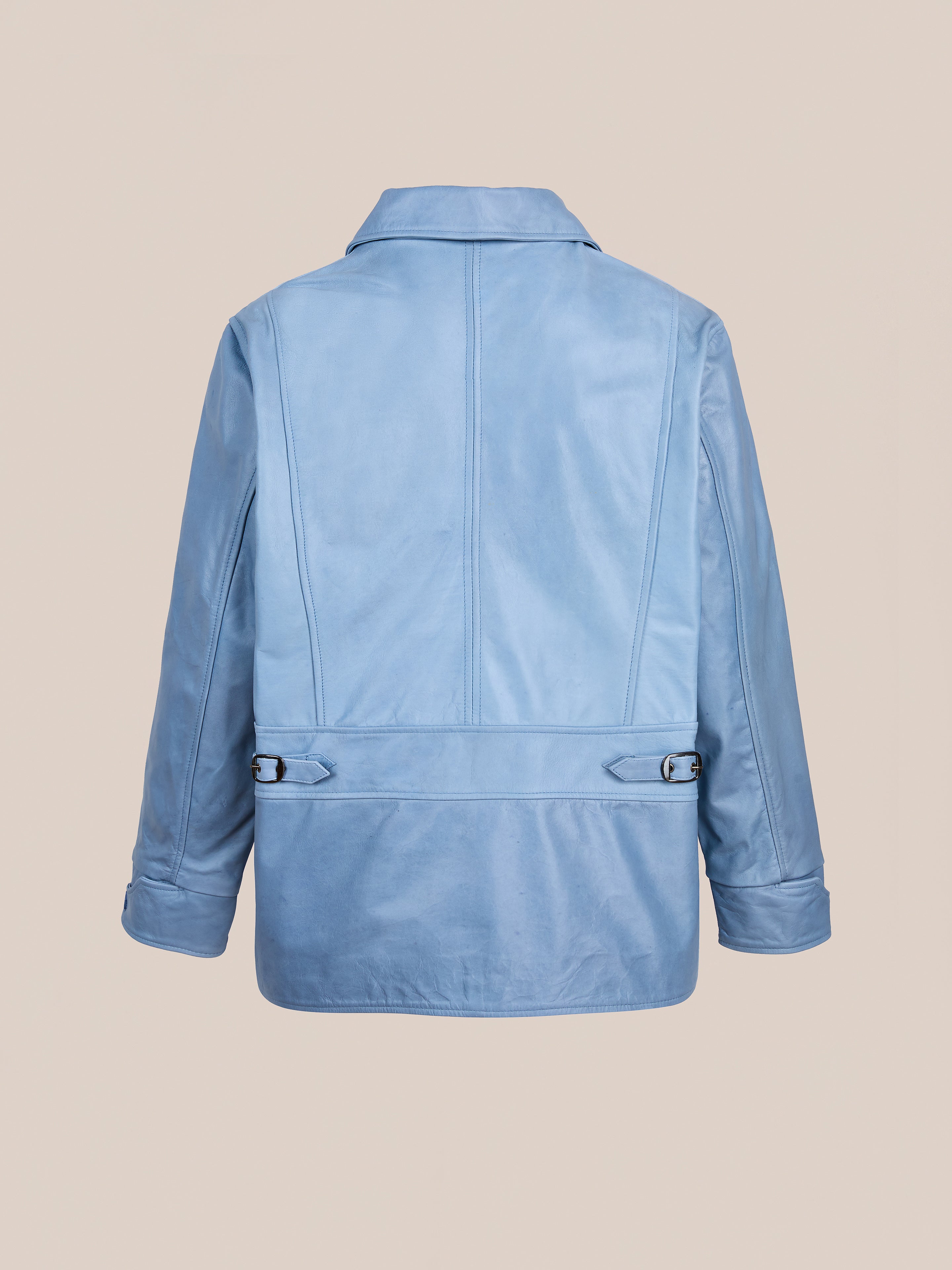 The FOUND Leather Field Jacket is a light blue leather piece shown from the back with a collar, long sleeves, and adjustable waist straps for a relaxed, unisex fit.