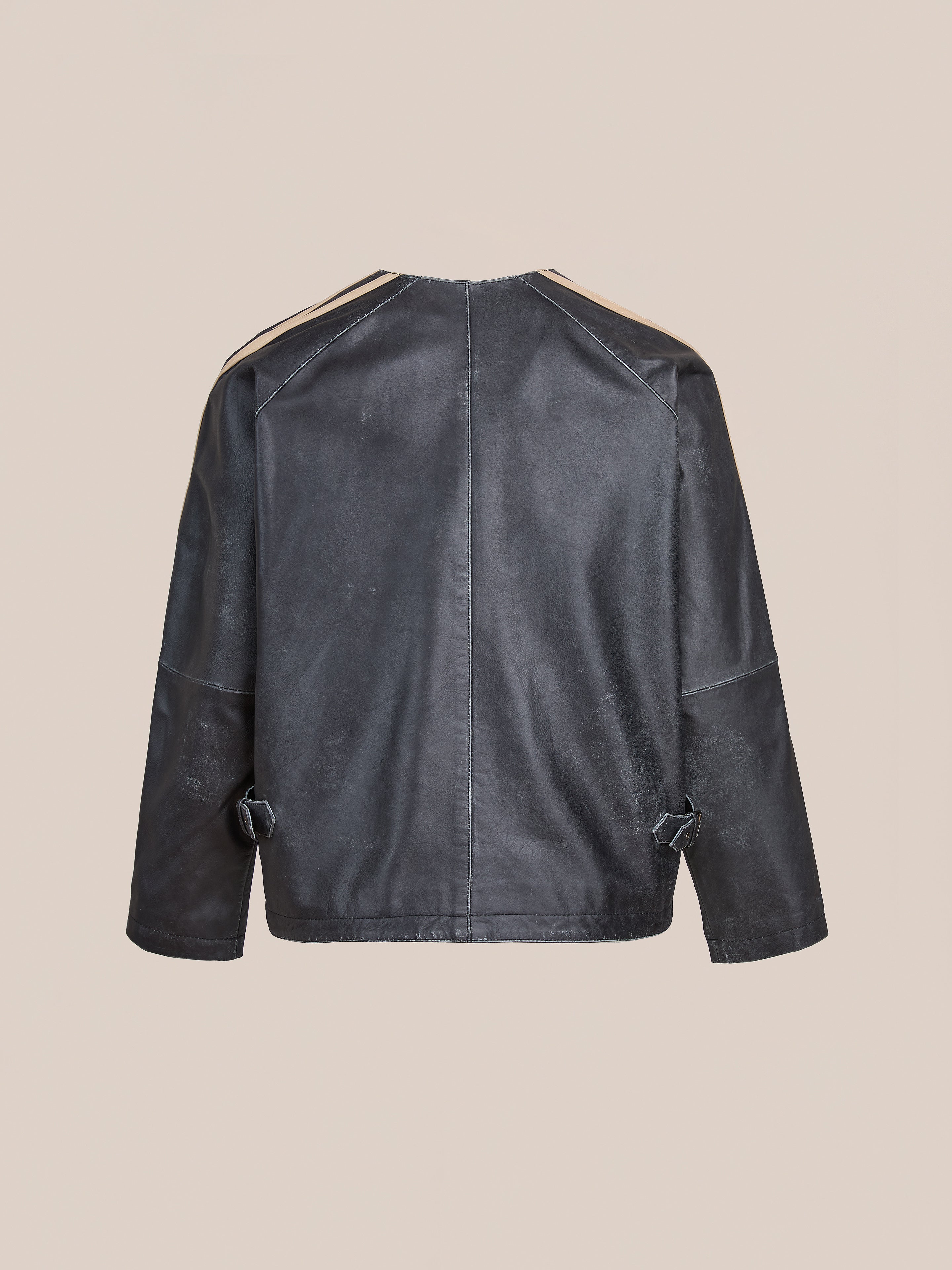 Back view of the FOUND Leather Track Jacket, a unisex design with long sleeves, visible seams, and adjustable side straps, shown against a plain beige background.
