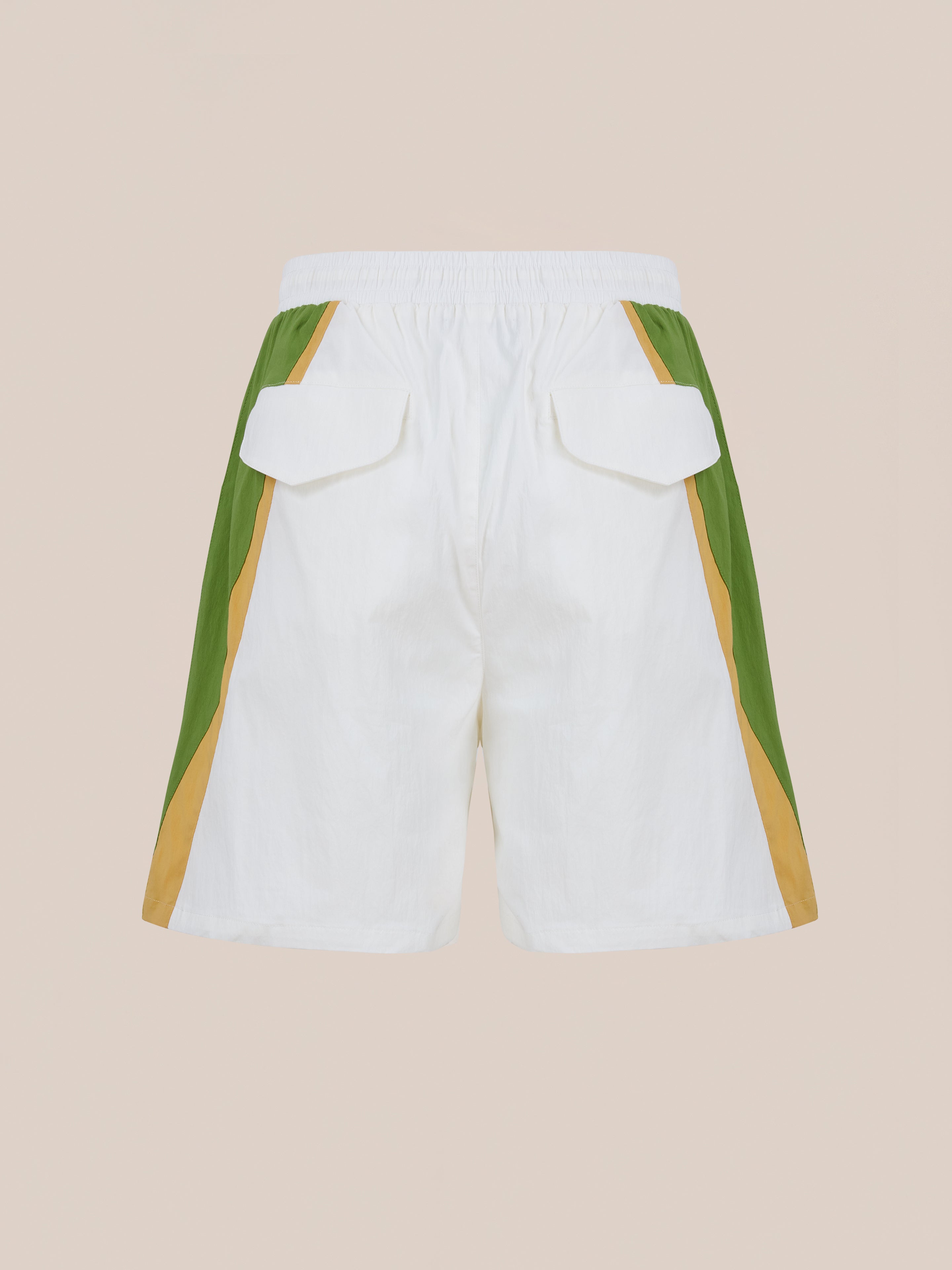 Found Legacy Cricket Track Shorts: White vintage-style shorts with green and tan side panels, elastic waistband, and two back flap pockets, shown on a neutral background.