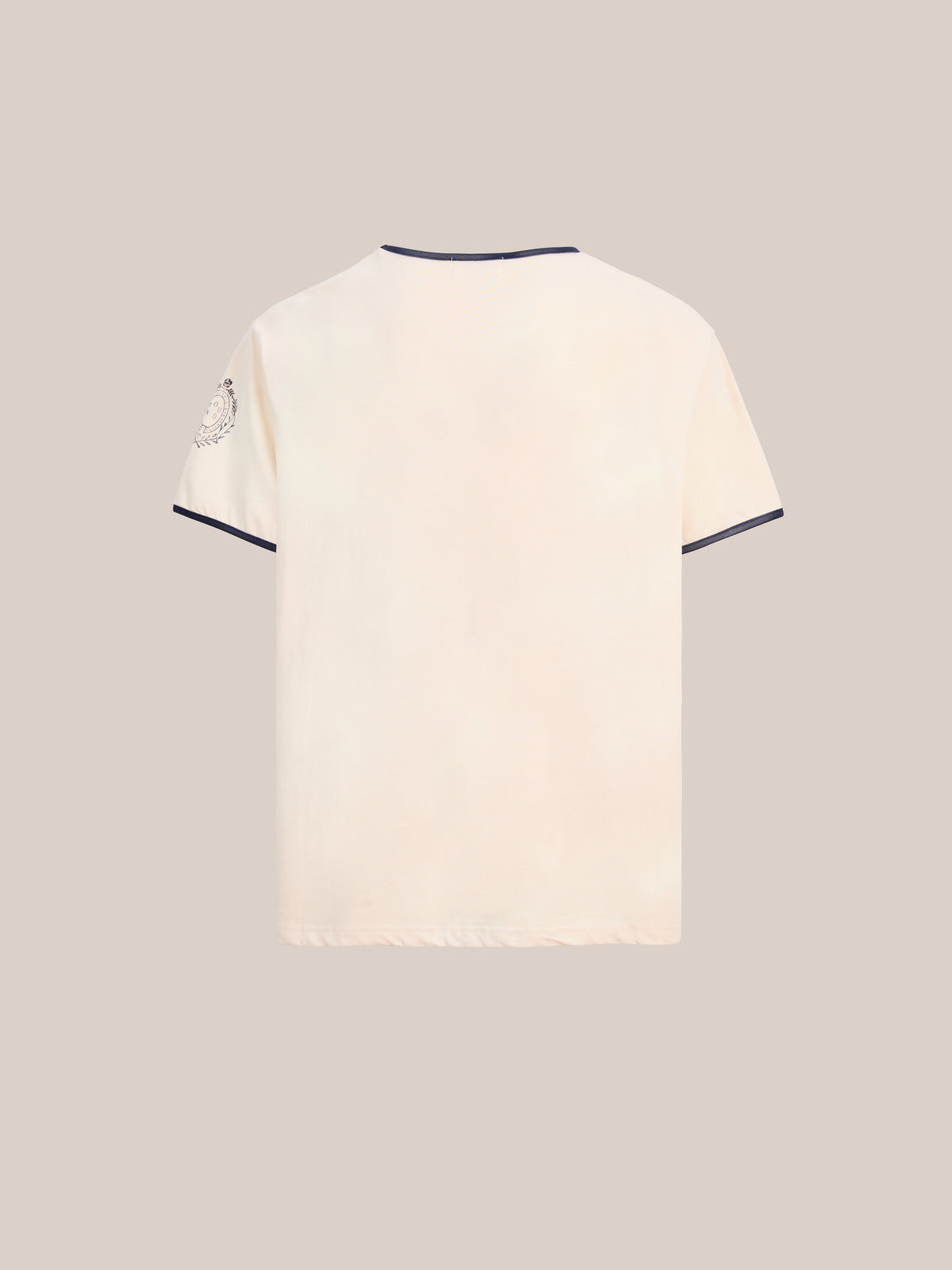 Back view of the FOUND Logo Felt Patch Ringer Tee, an off-white unisex T-shirt with dark trim on the collar and sleeves, featuring embroidered lettering and a small felt patch emblem on the left sleeve. Designed in a relaxed fit for everyday comfort.