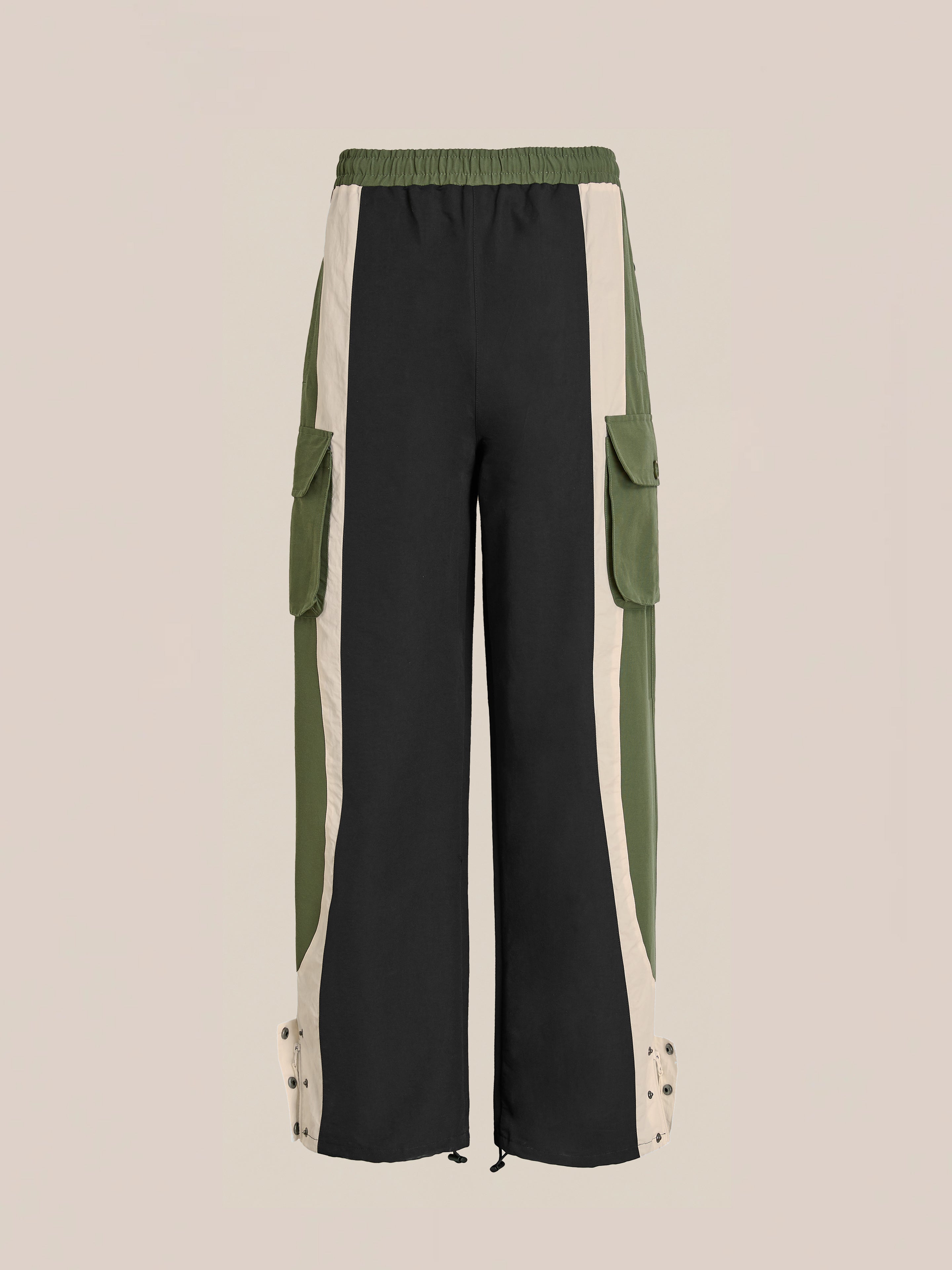 The Found Sporting Club Track Pants blend vintage athletic style with utility, featuring a unisex fit, wide legs, elastic waistband, black/olive/beige color-blocking, side pockets, and snap buttons at the ankles.