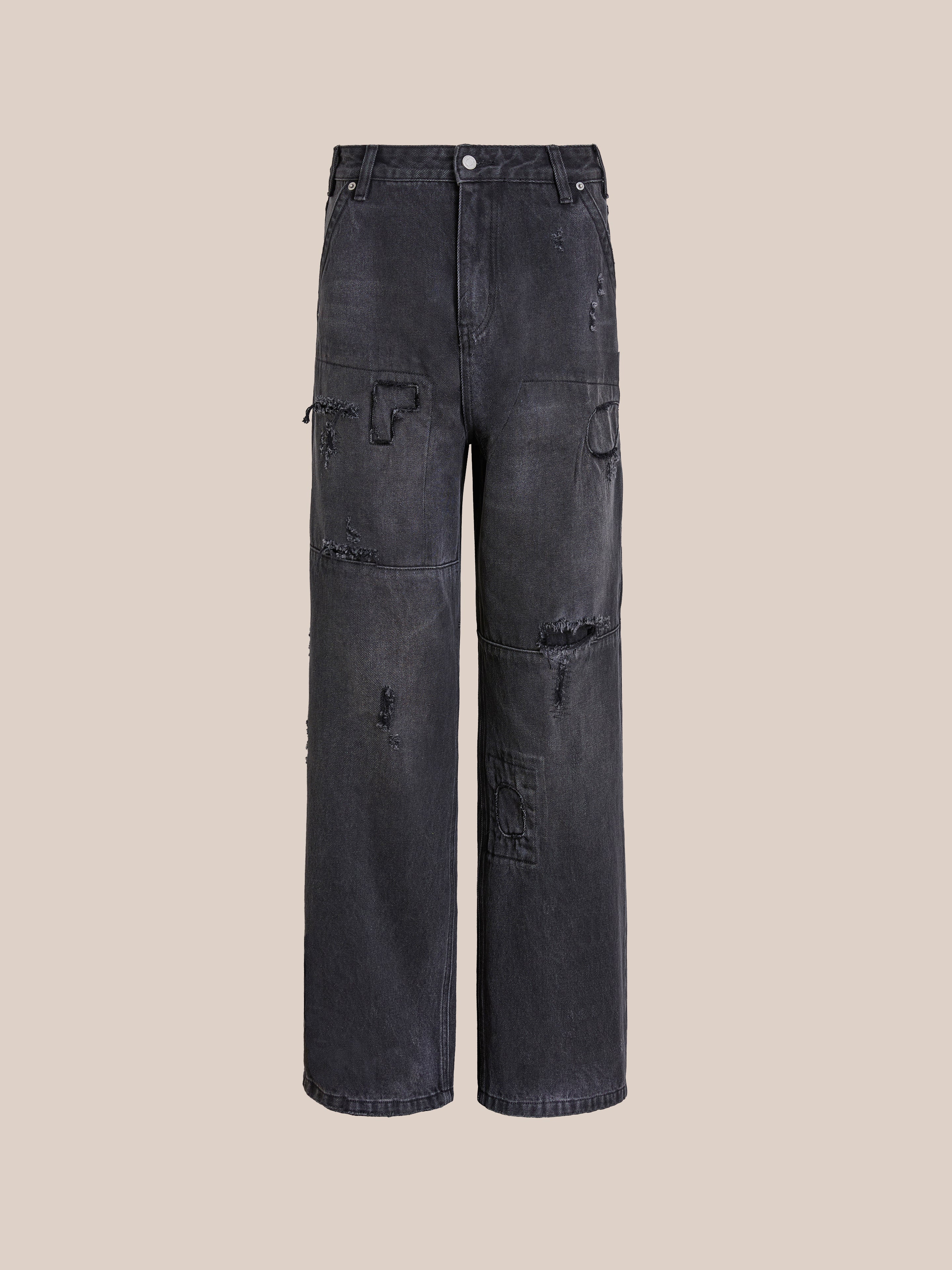 The FOUND Painter Repaired Jeans feature a black patchwork design, wide legs, distressed vintage denim accents, side pockets, and a button closure, shown against a plain beige background.