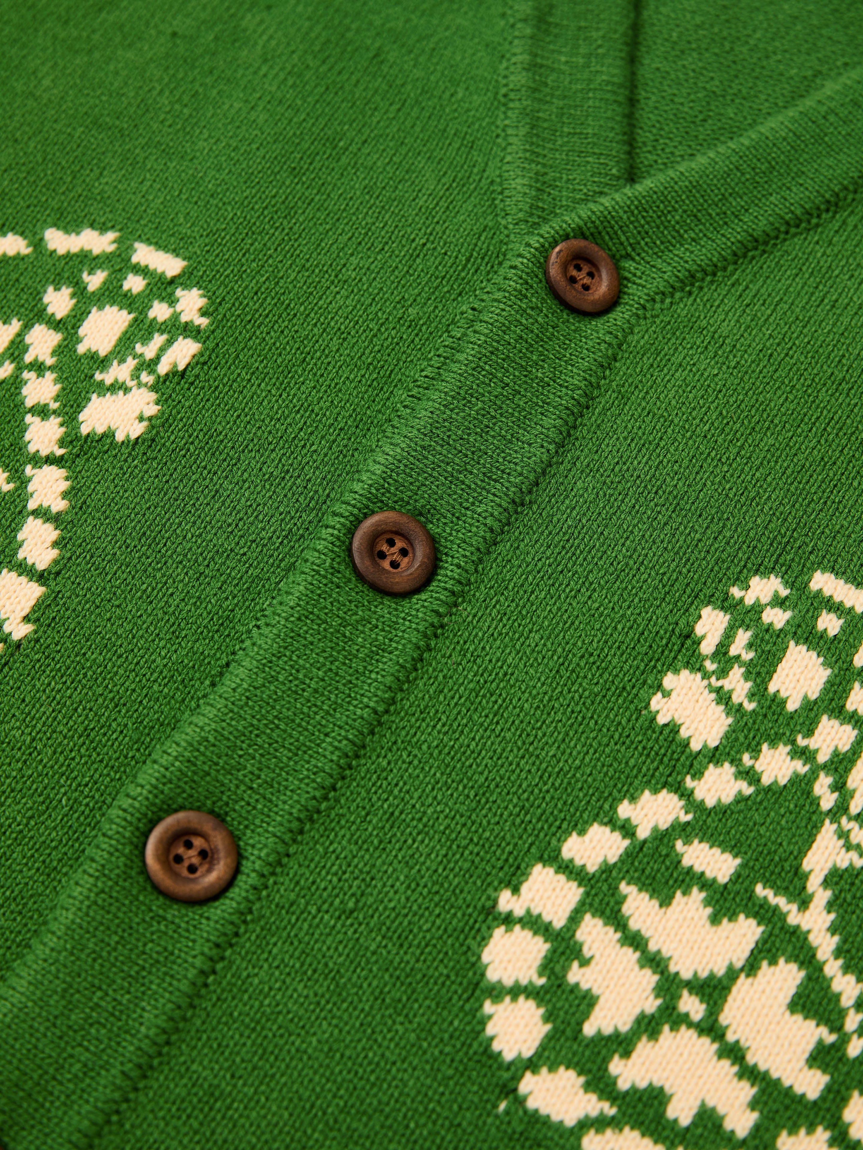 Close-up of FOUND’s Paisley Knit Cardigan, a green unisex cotton knit with brown buttons and white patterned designs, highlighting its cozy style.