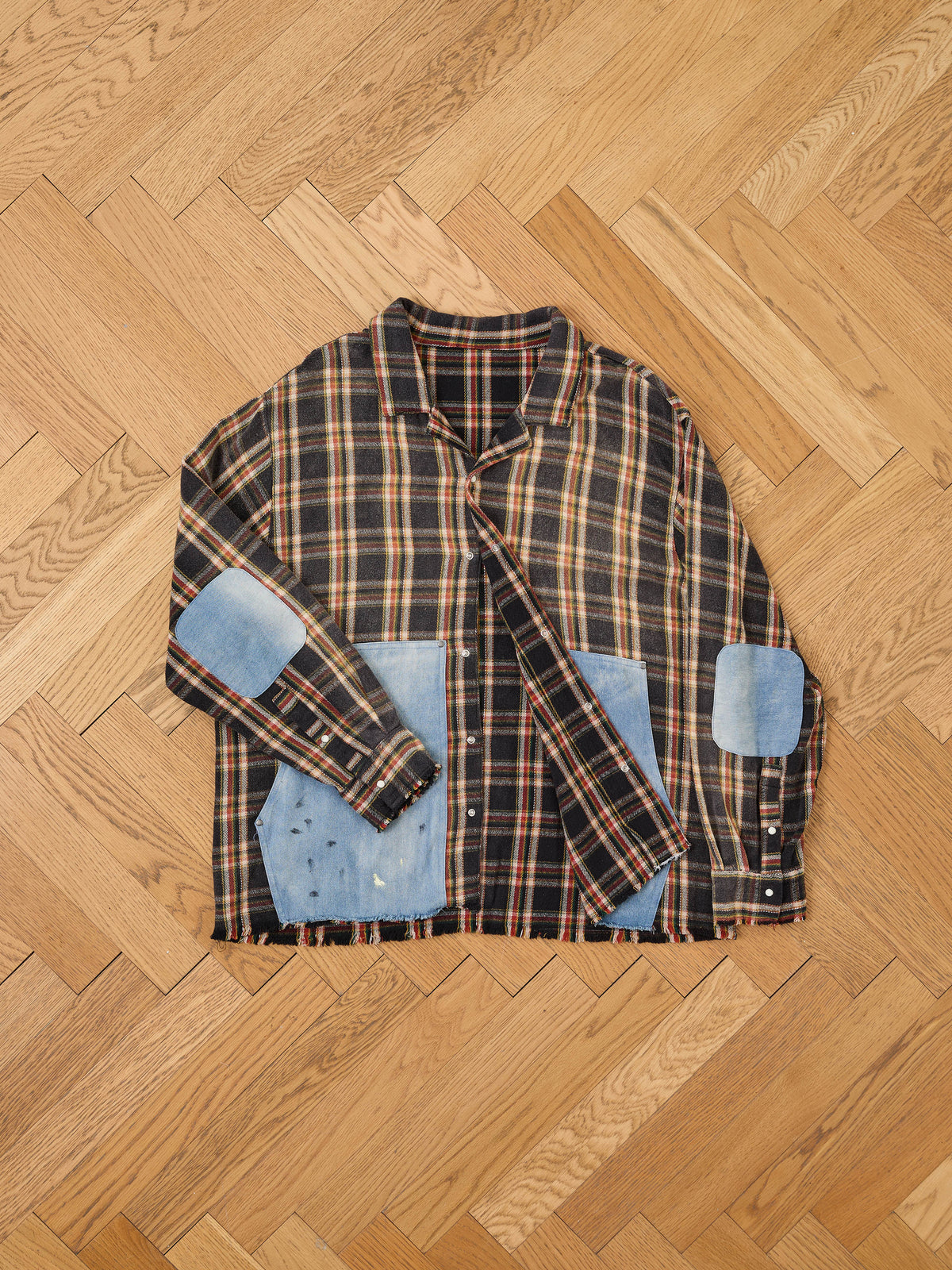 FOUND Plaid Denim Shirt, unisex relaxed fit with blue denim elbow and pocket patches, shown laid flat on a wooden parquet floor.