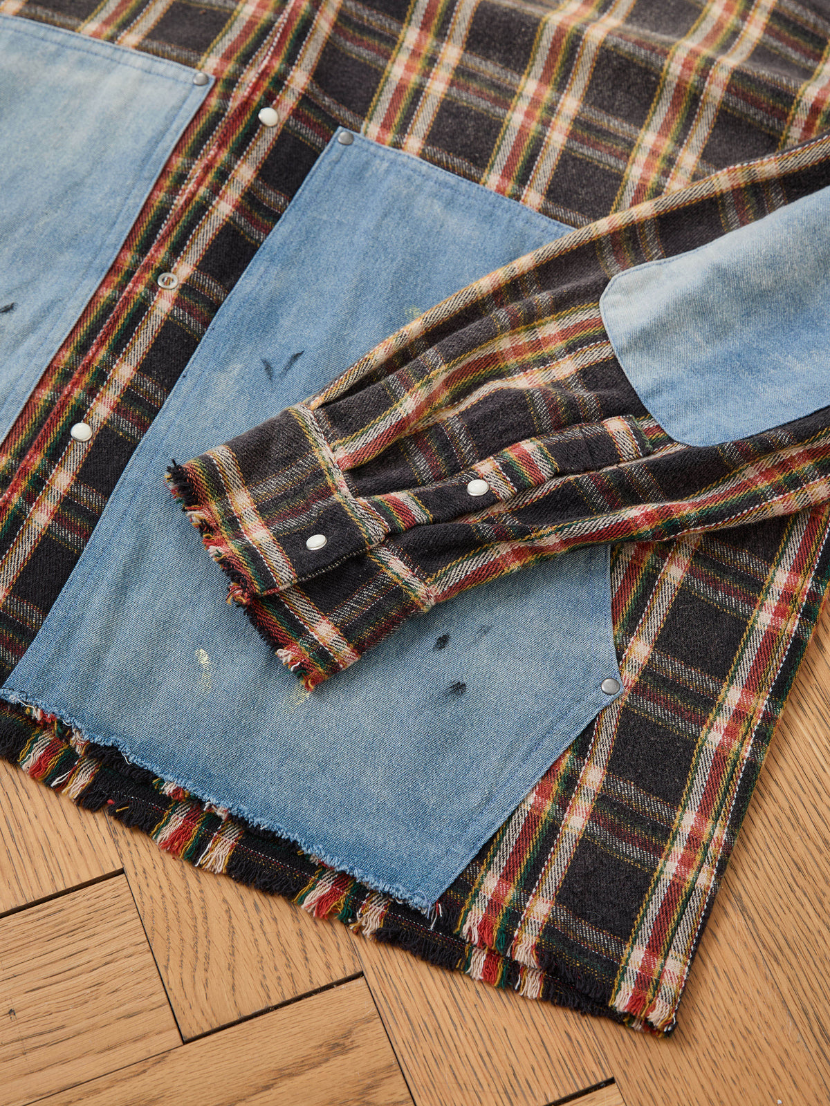 FOUND Plaid Denim Shirt features distressed denim patches, metal snaps, and frayed edges for a unisex relaxed fit, shown on a wooden floor.