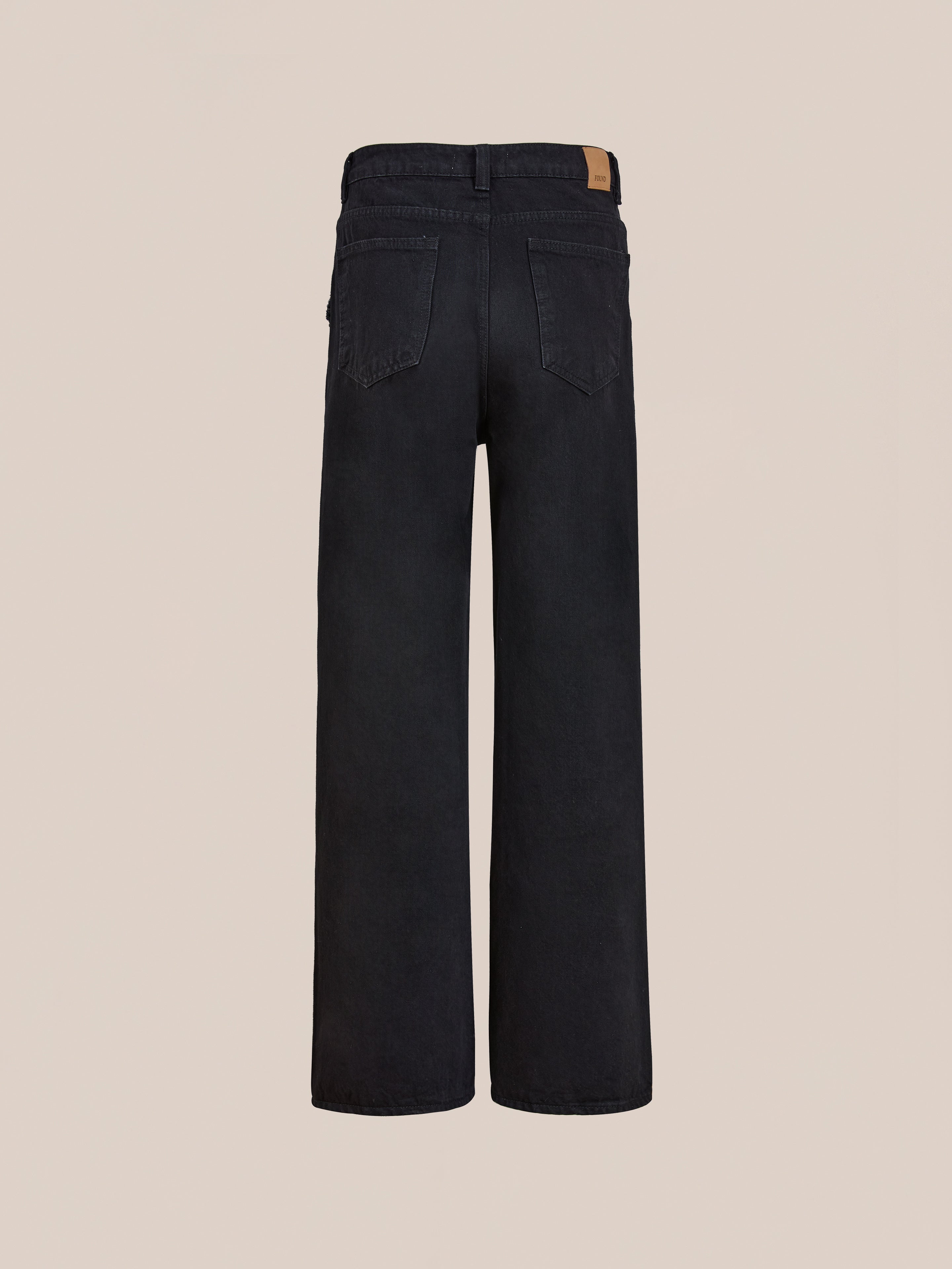 A pair of Found Pleated Relaxed Fit Jeans in black, shown from the back, featuring two rear pockets and a brown patch on the waistband.