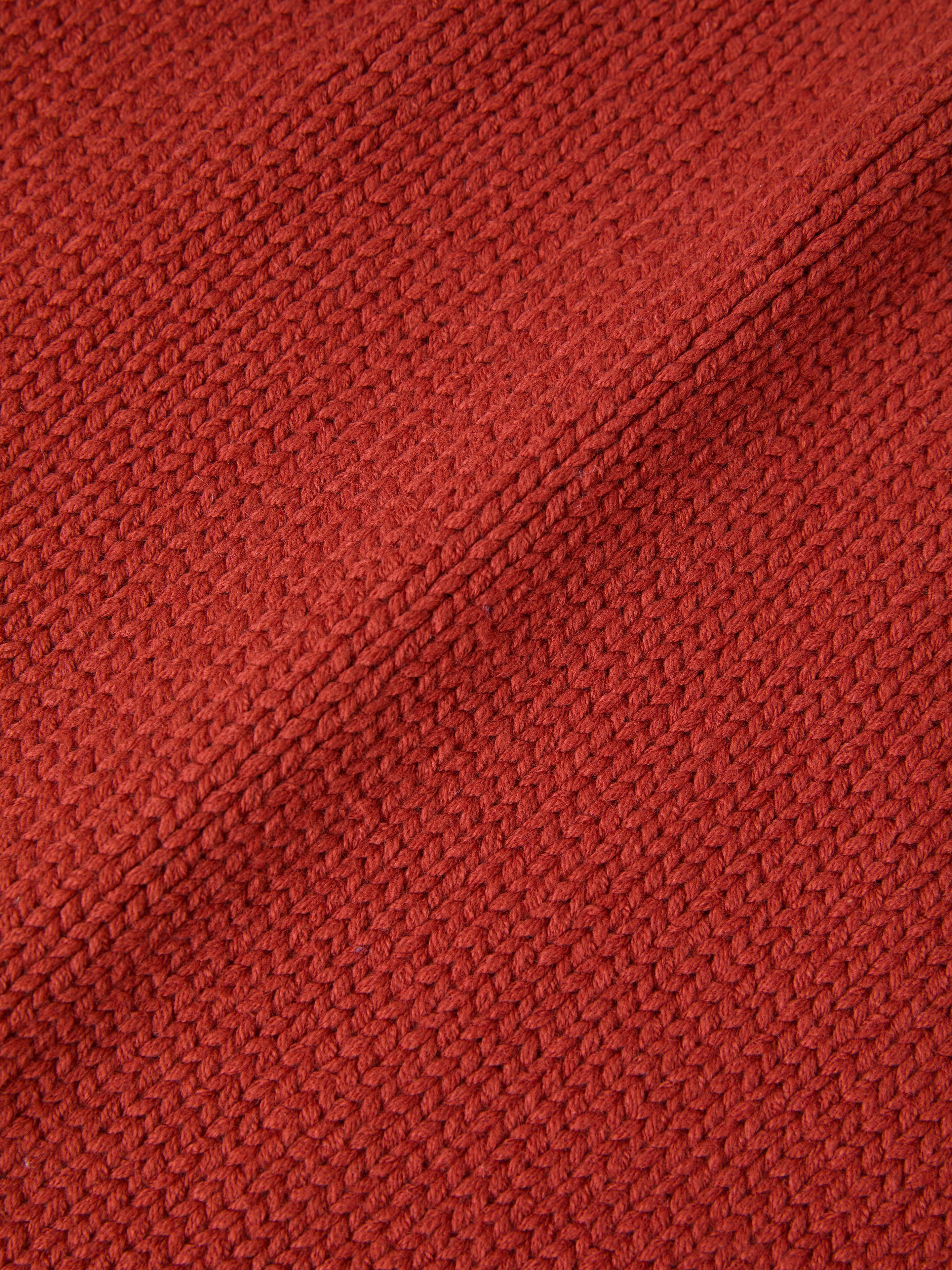 Close-up of the Hunter Knit Collared Cardigan by FOUND, showcasing a heavy knit cotton fabric with a red textured finish and a charming diagonal seam.