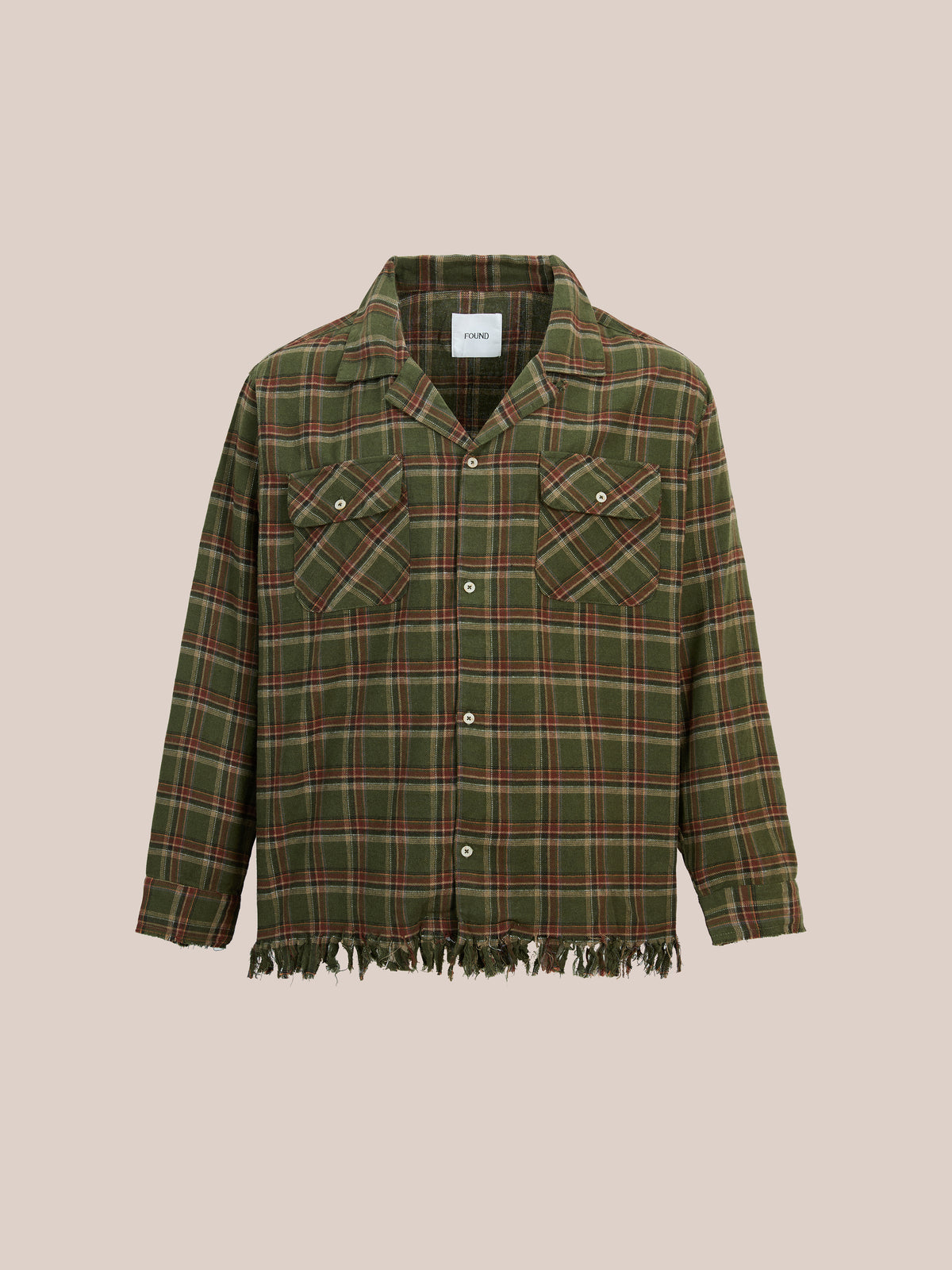 FOUND Raw Cut Fringe Plaid Camp Shirt in green and red with long sleeves, two chest pockets, and frayed hem on a beige background.