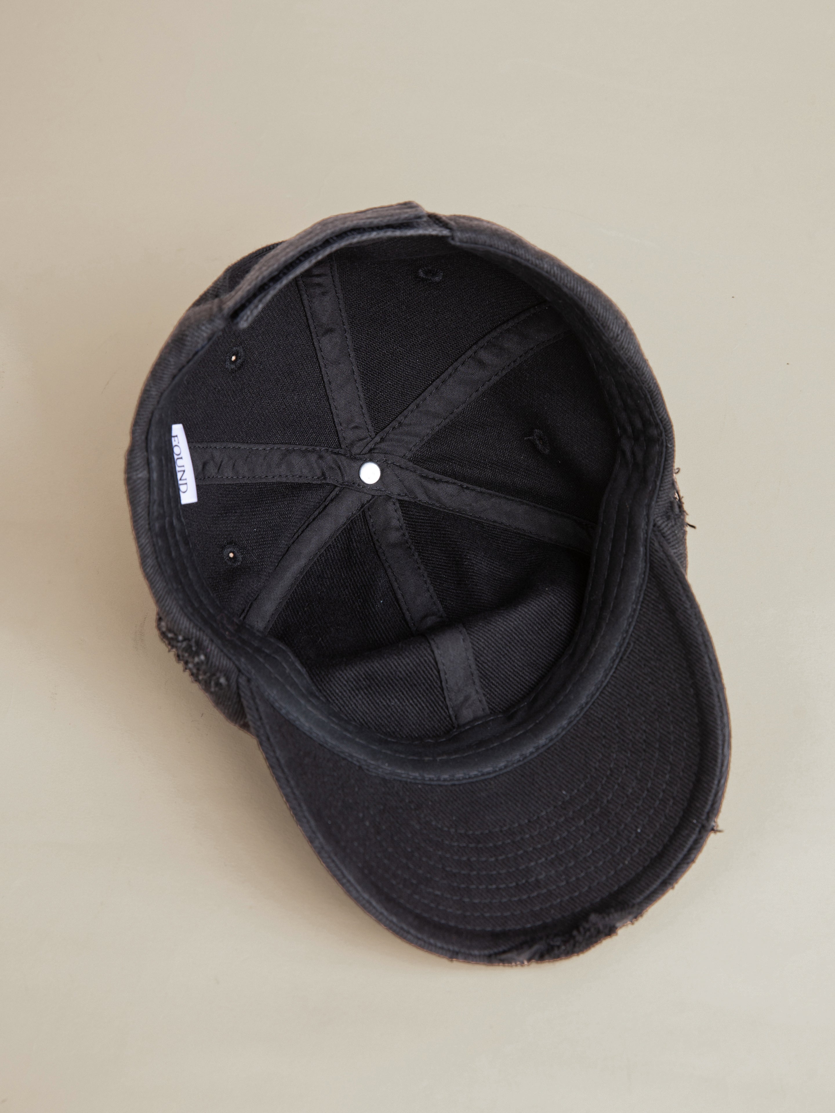 The FOUND Distressed Pin Cap is displayed upside down on a light-colored surface, revealing its inner structure and stitching.