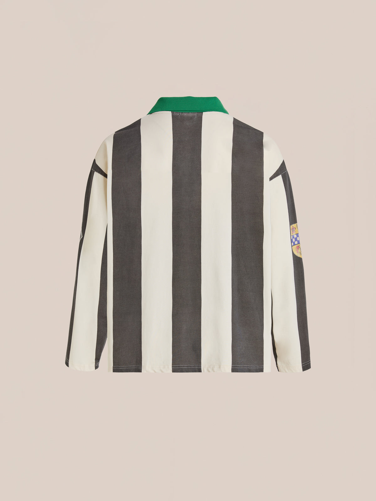 The FOUND Striped Sport LS Jersey is a relaxed fit, unisex top with black and white vertical stripes, a green collar, and a right sleeve patch, shown from the back.