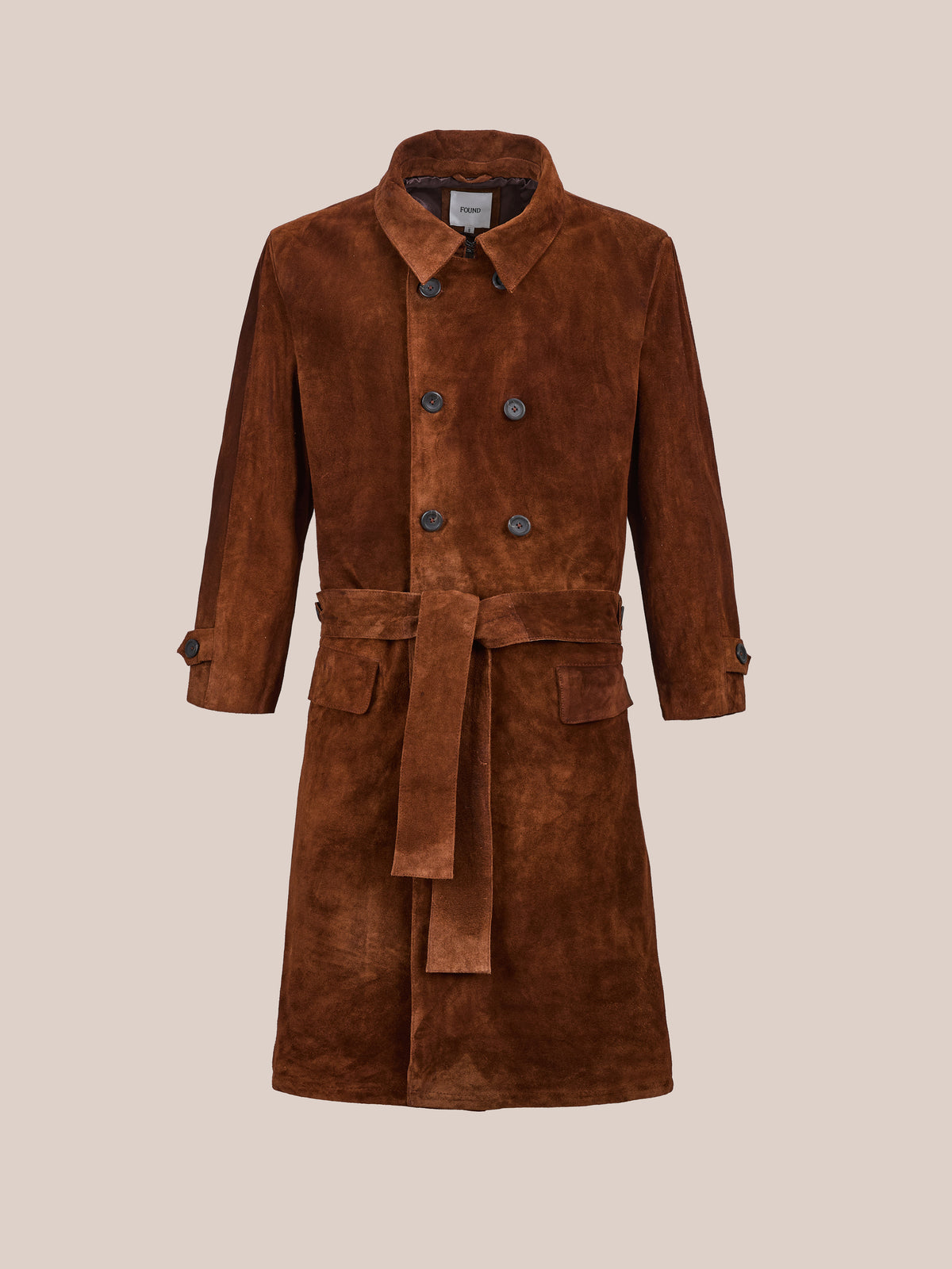 The Belted Suede Trench Coat by FOUND features button closure, belted waist, and two front pockets, shown against a plain beige background.
