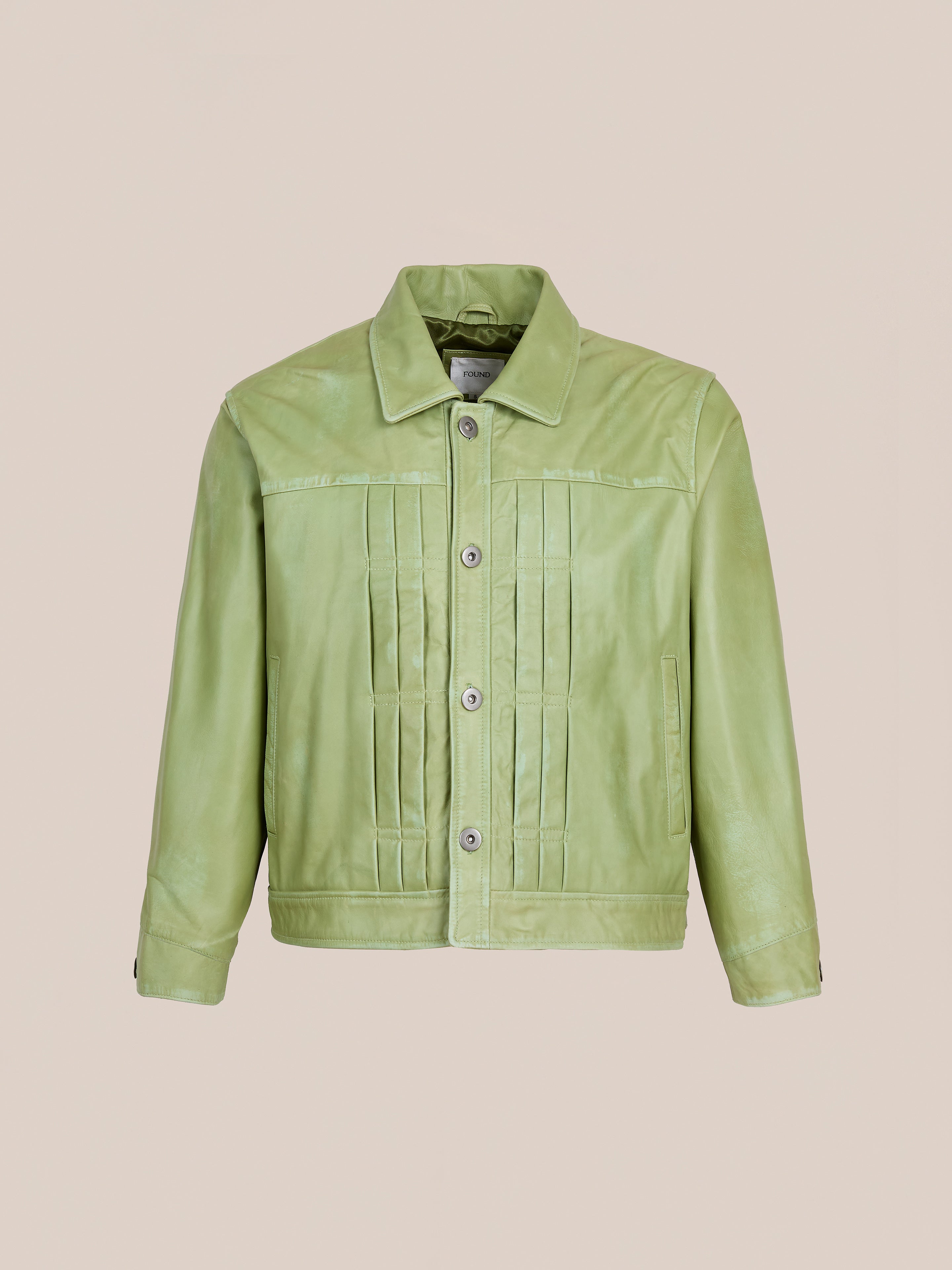 The FOUND Trucker Leather Jacket in light green washed leather features a collar, button-down front, and vertical stitched chest detailing in a relaxed fit, shown on a plain beige background.