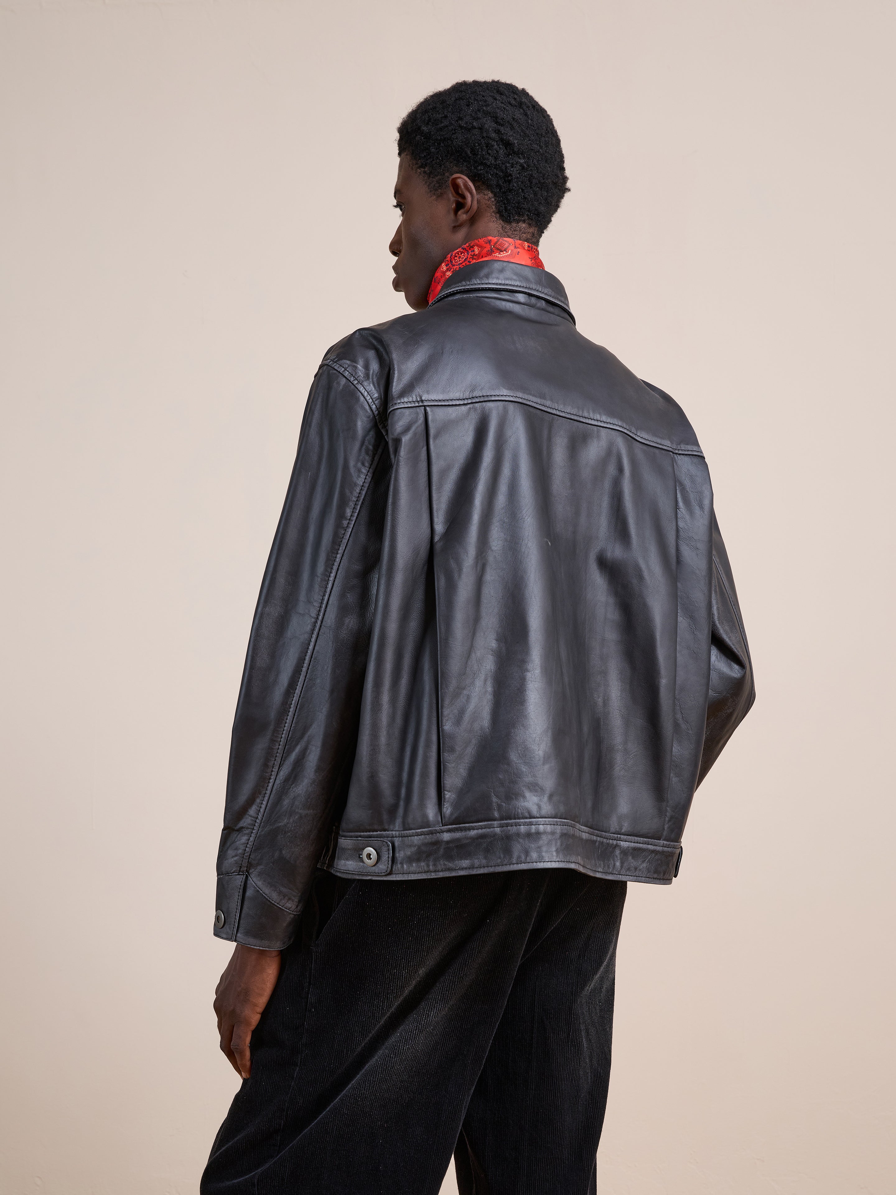 A person wearing the FOUND Trucker Leather Jacket and black pants stands with their back to the camera against a plain beige background.