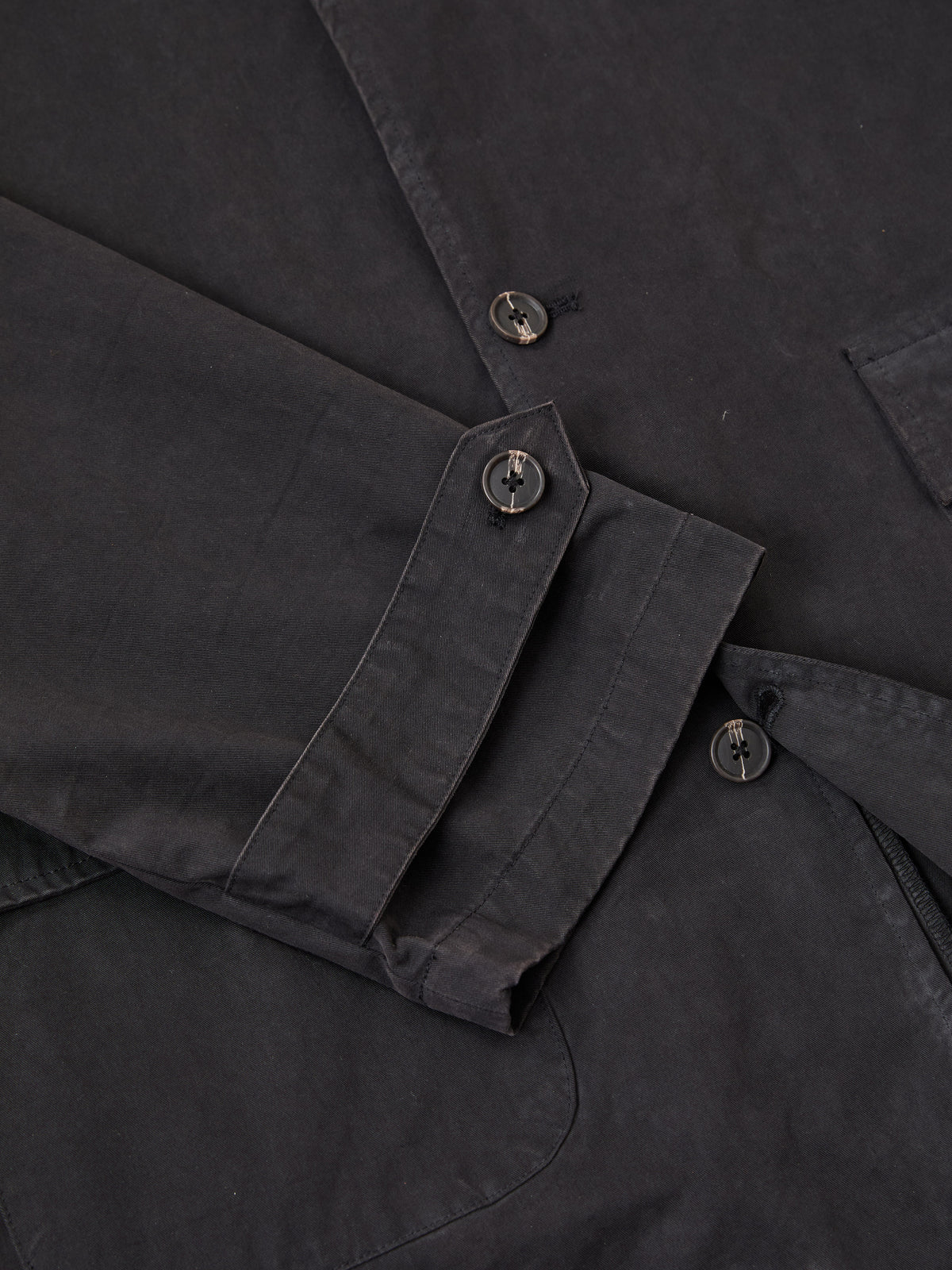 Close-up of the FOUND Twill Work Trench Coat, highlighting the cuff with two black buttons and part of a pocket.