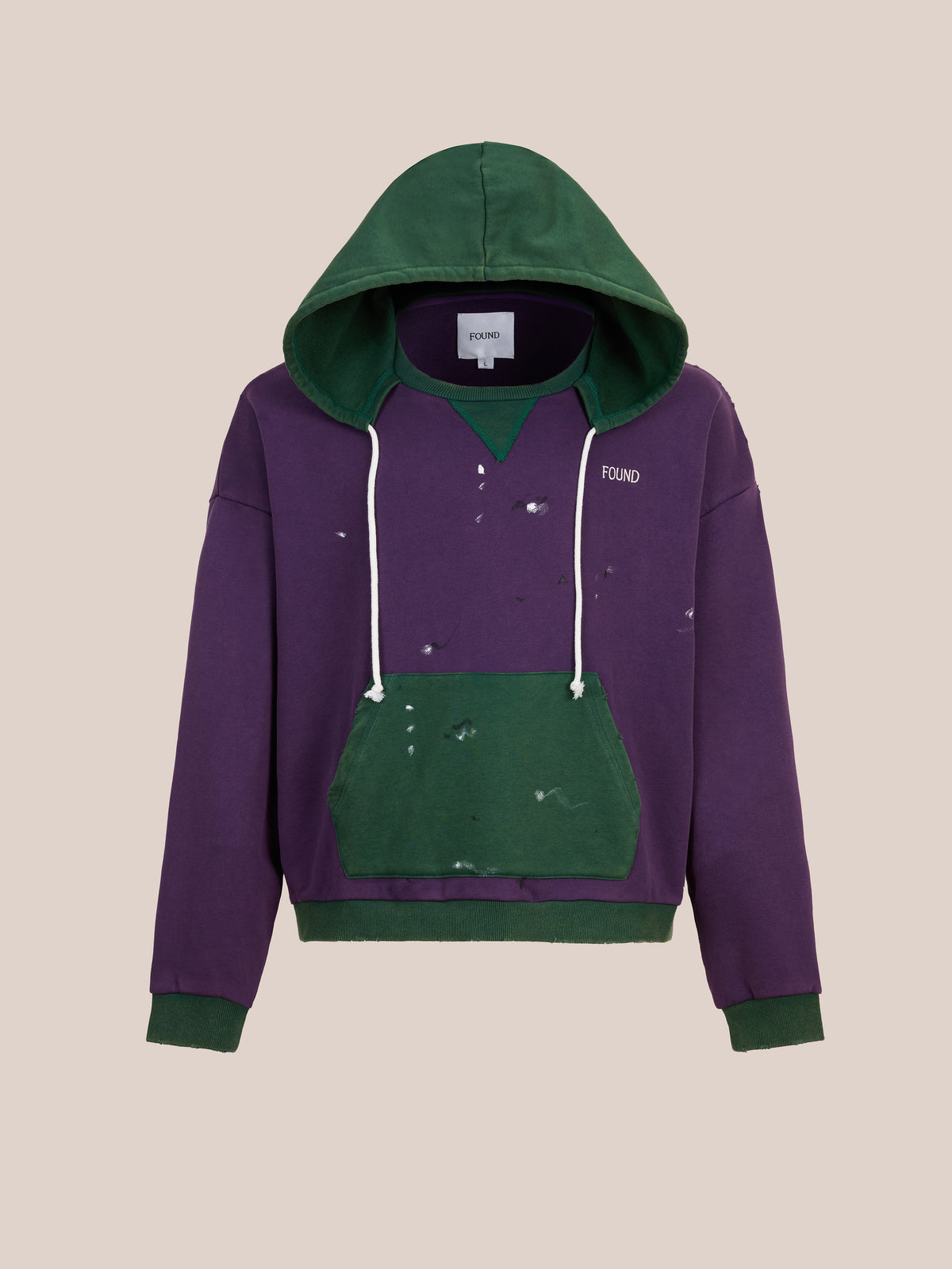 The FOUND Two Tone Painter Hoodie features purple and green tones, a front pocket, white drawstrings, distressed details, and a relaxed unisex fit.