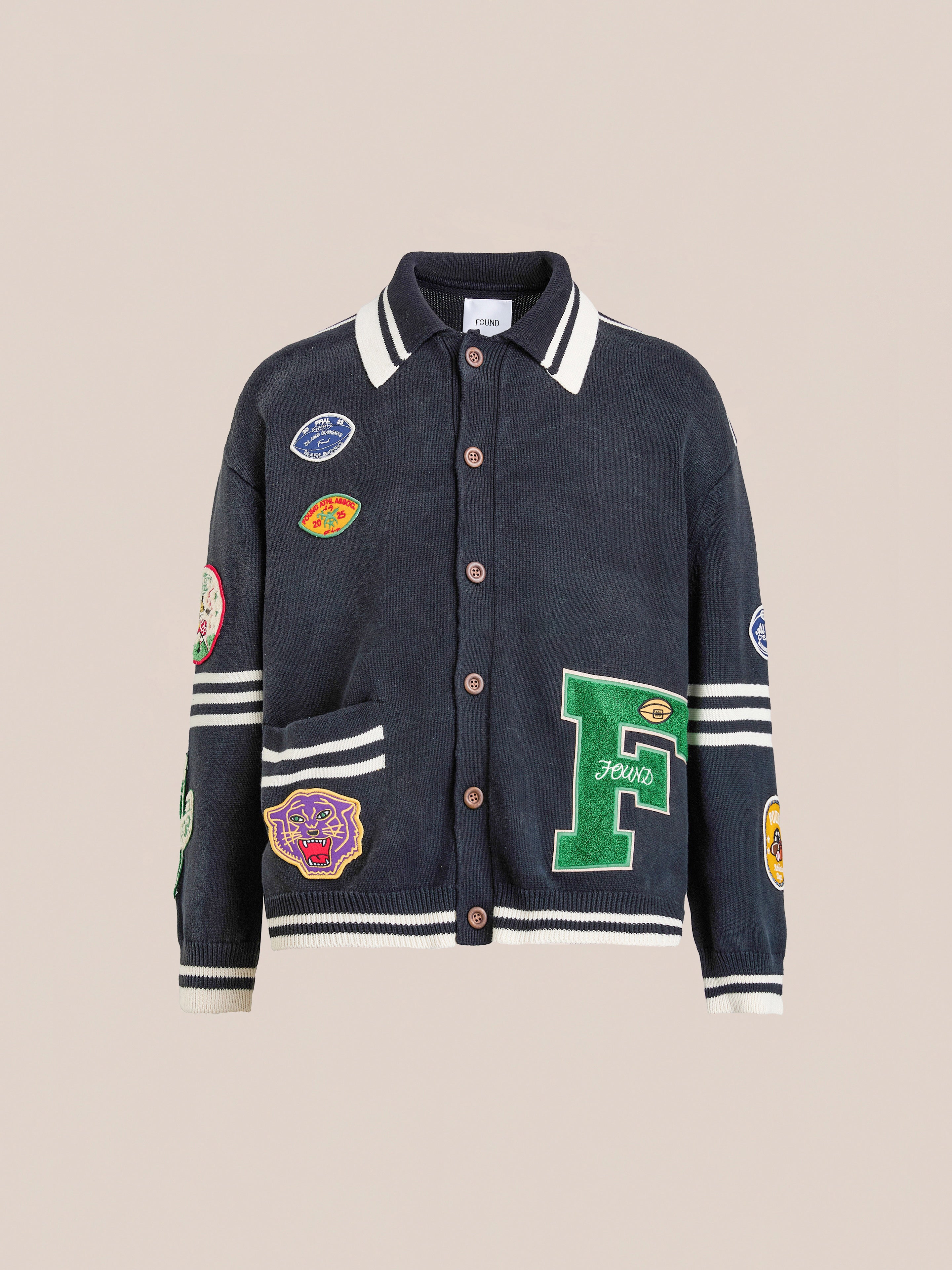 The FOUND Varsity Patch Collared Cardigan is crafted from soft black cotton knit with white stripes, button closure, and colorful chenille patches embroidered on the front, sleeves, and pockets.