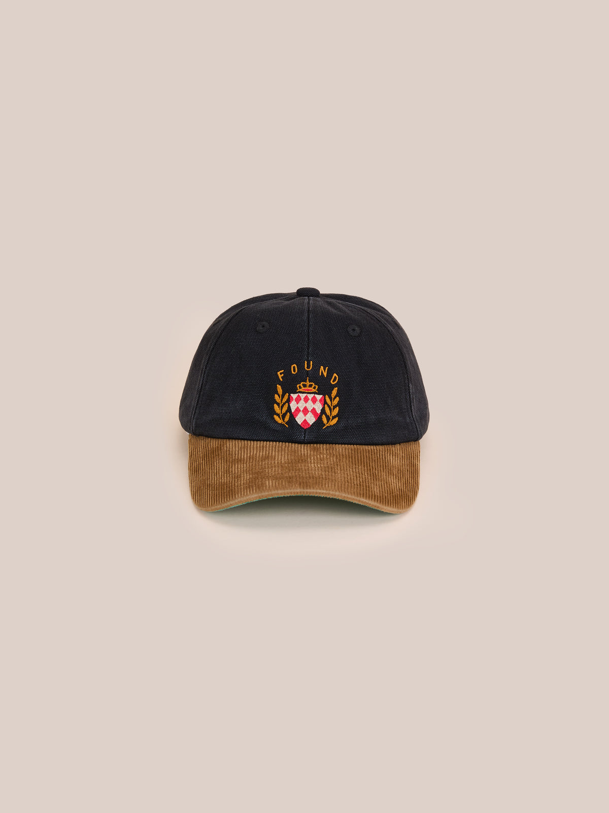 The Found Vintage Club Cap in black and brown corduroy features an embroidered crest, laurel leaves, and “FOUND” text on the front.