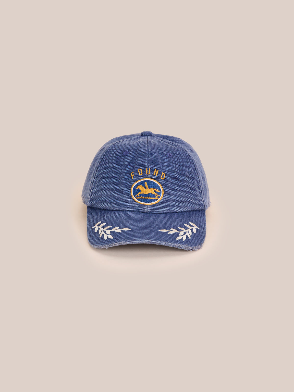 The Vintage Club Cap by Found features a blue design with yellow embroidered dog, “FOUND” text, white laurel on the brim, beige back, and an adjustable leather strap.