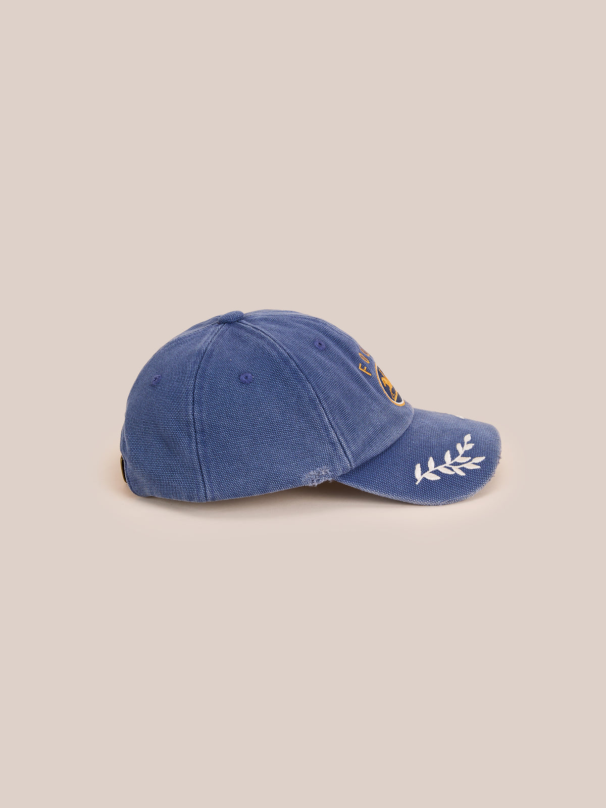 The Vintage Club Cap by Found features subtle distressing, floral embroidery on the brim, a front patch, and an adjustable leather strap.