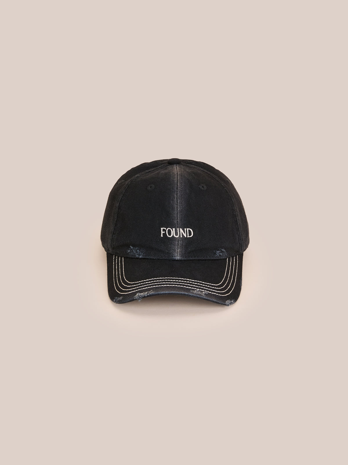The Washed Logo Cap by Found features “FOUND” embroidered in white and an adjustable leather strap, shown on a plain beige background.