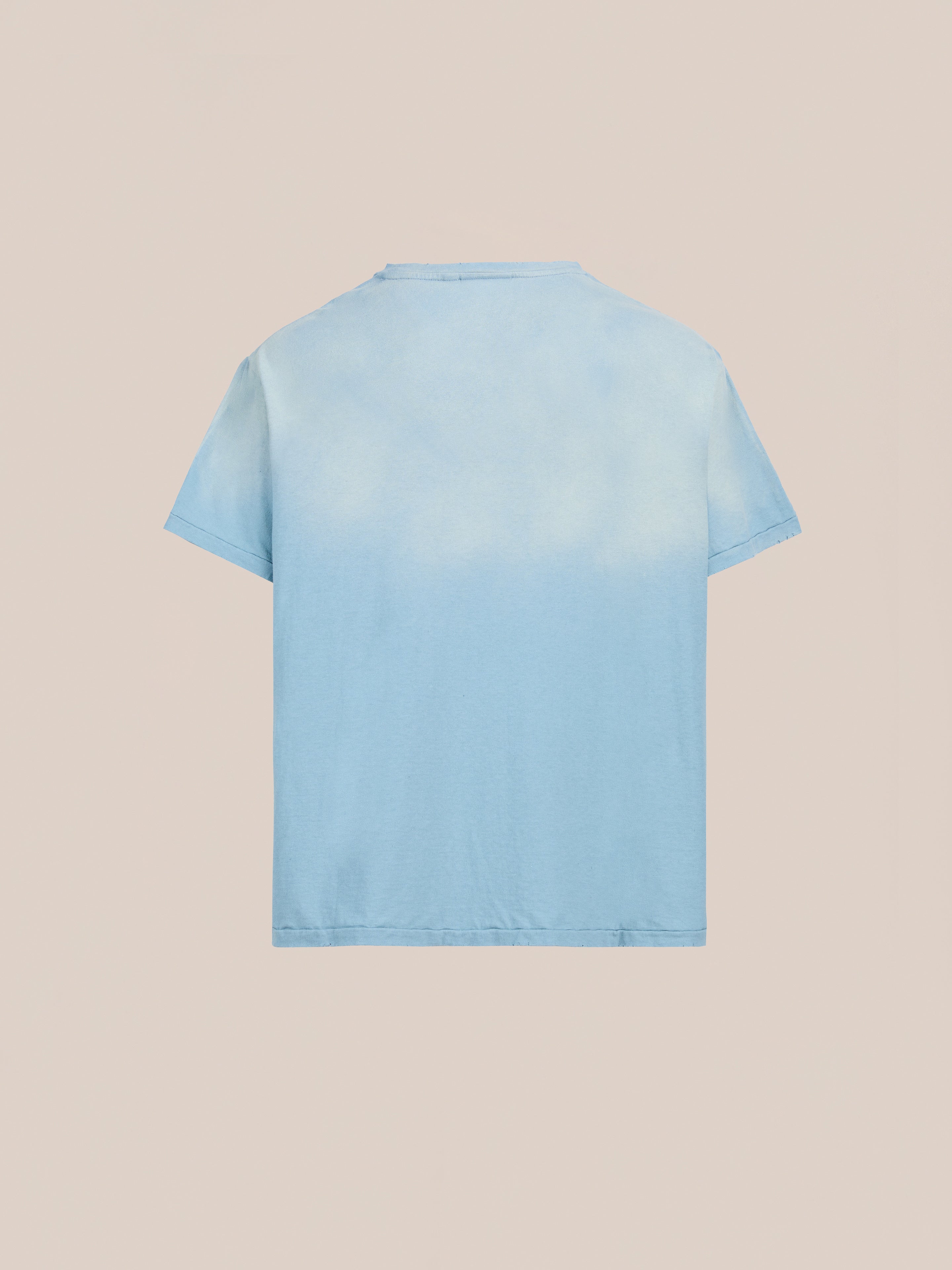 The FOUND Weathered Pocket Tee is a soft cotton, short-sleeve crew neck with a light blue and white gradient, shown from the back on a beige background.