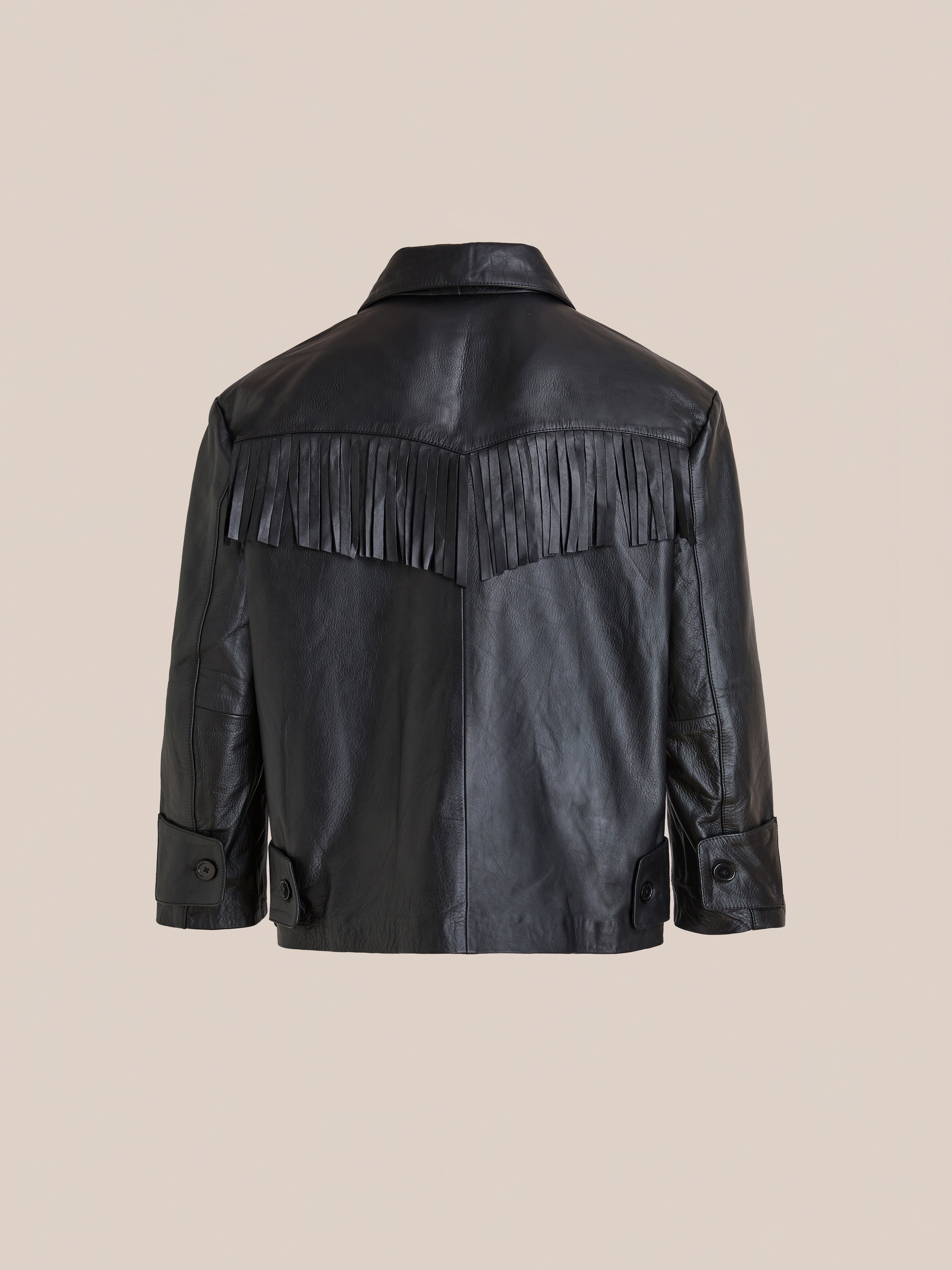 The FOUND Hand Embroidered Leather Fringe Jacket in black genuine cowhide features fringe across the upper back and arms, shown against a plain beige background.