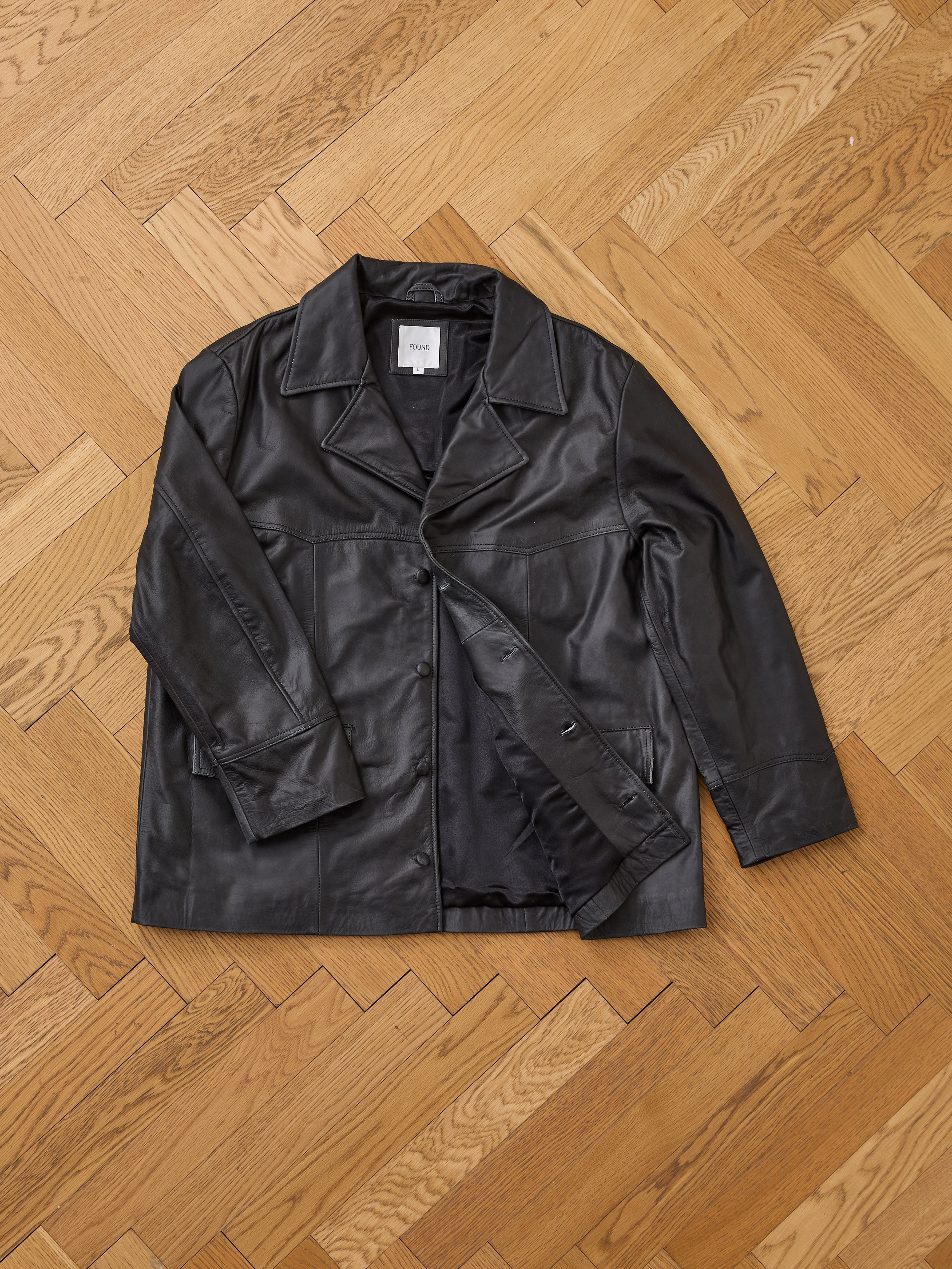 The FOUND Western Oversized Leather Blazer is displayed laid flat on a light wooden herringbone floor.