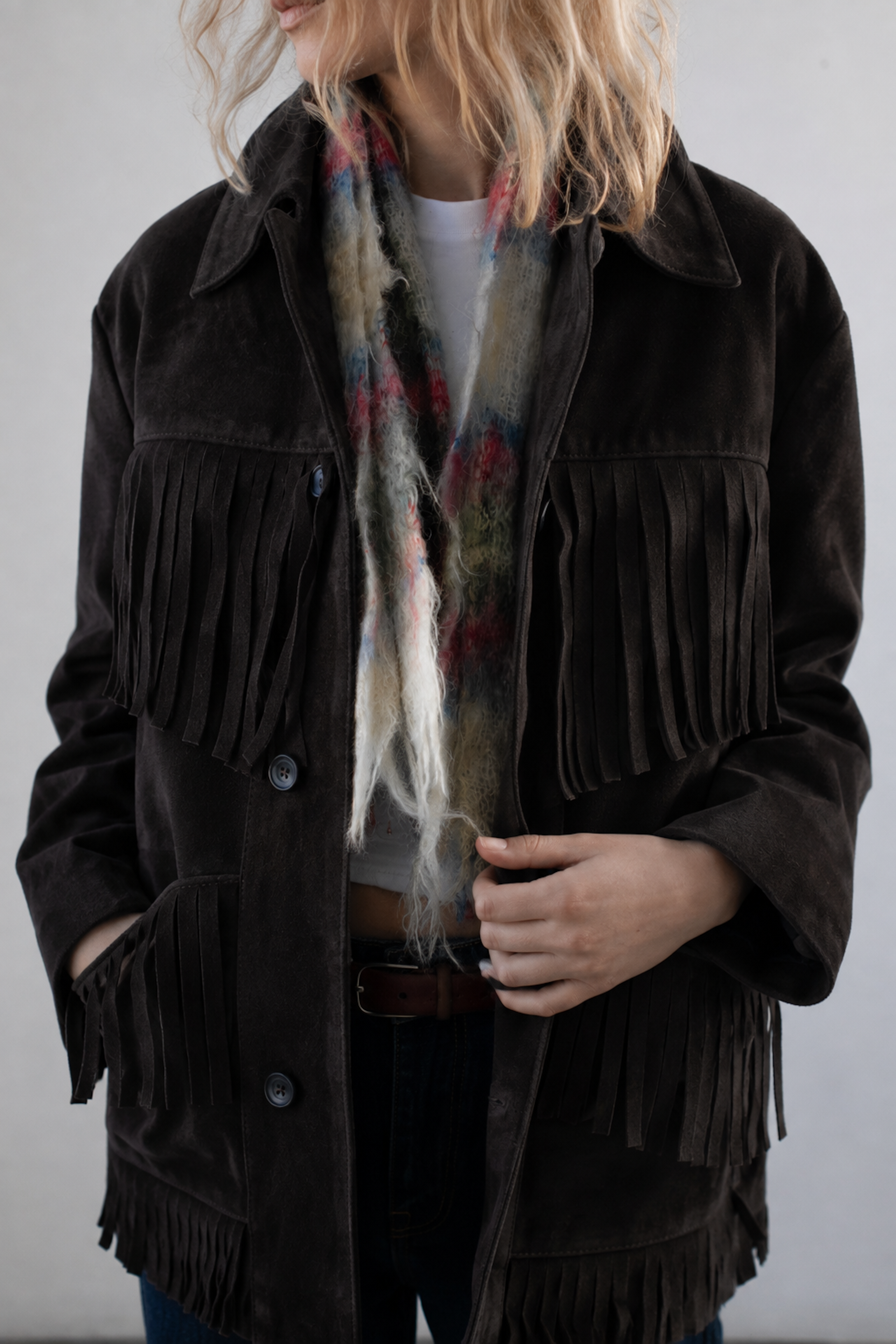 A person wearing the FOUND Western Suede Fringe Jacket styled with a colorful wool scarf, standing against a plain background.
